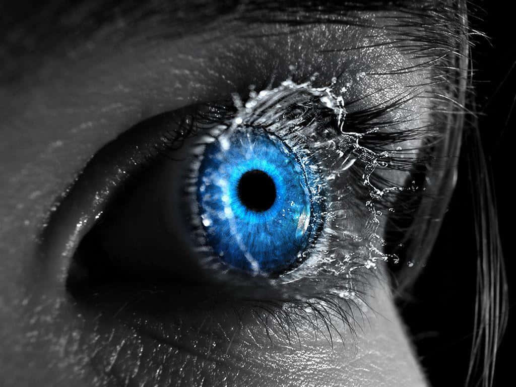 Eyes 桌布 壁紙 — 一個引人注目的特寫，一隻鮮豔的藍色眼睛，水戲劇性地濺在其表面，背景為黑白。