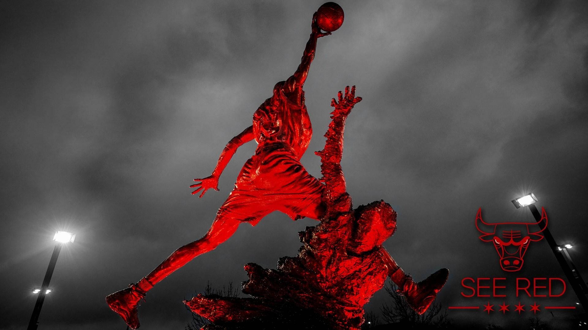 Chicago Bulls 桌布 壁紙 — 一個引人注目的紅色雕像，描繪籃球運動員在半空中越過防守者灌籃，背景是陰鬱的灰階天空。