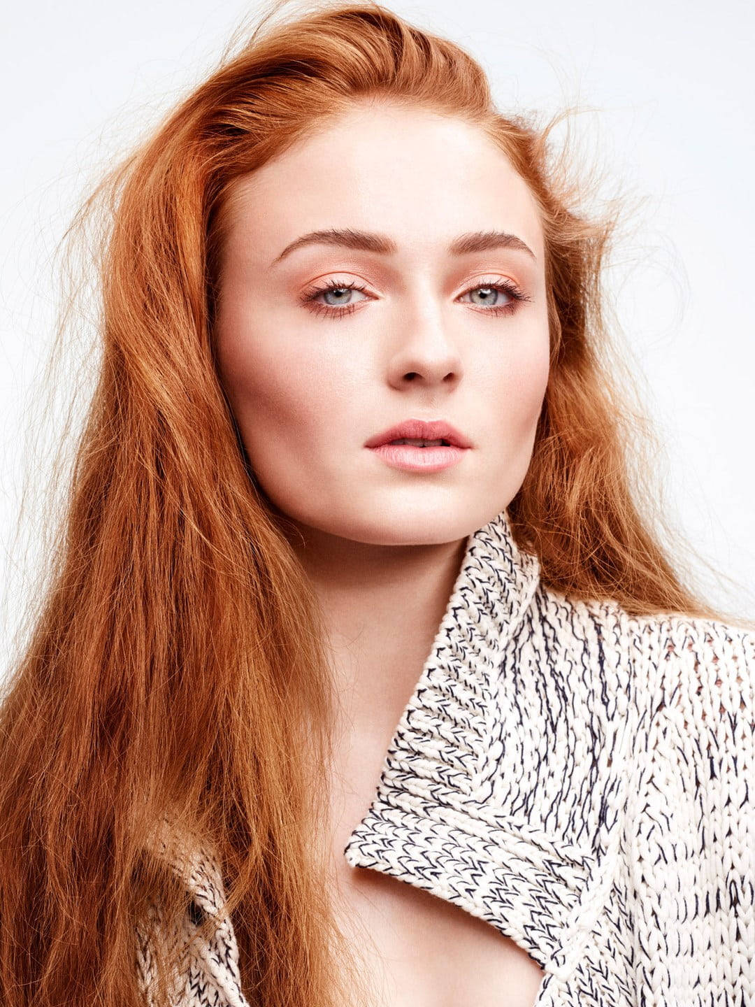 Sophie 桌布 壁紙 — 一個引人注目的肖像，一位擁有火紅頭髮和銳利藍眼睛的女性，穿著質感針織上衣，背景是純白色。