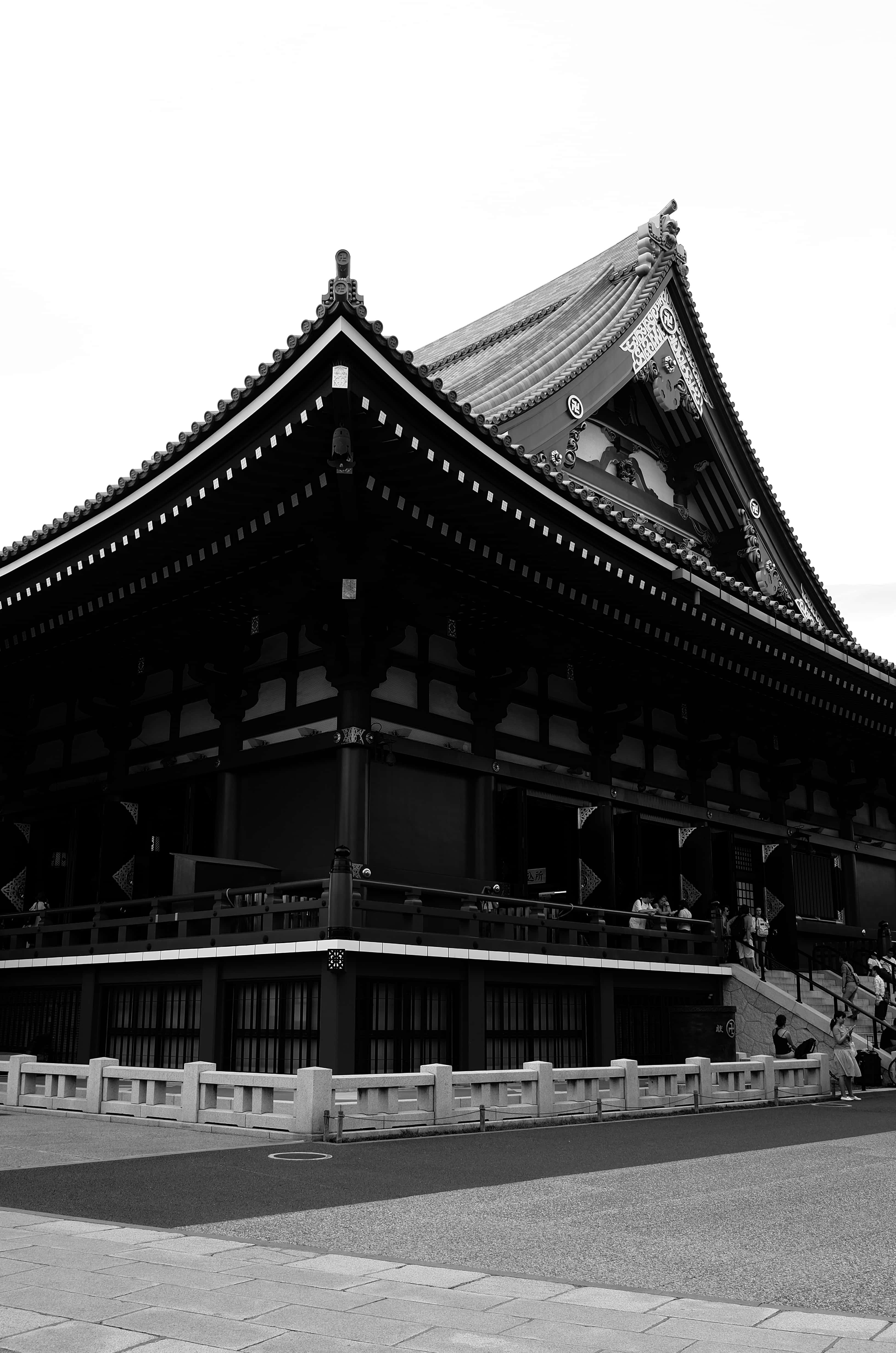 廟宇 桌布 壁紙 — 一個引人注目的黑白景觀，展示傳統日本寺廟，擁有華麗的屋頂線條和階梯上的訪客。