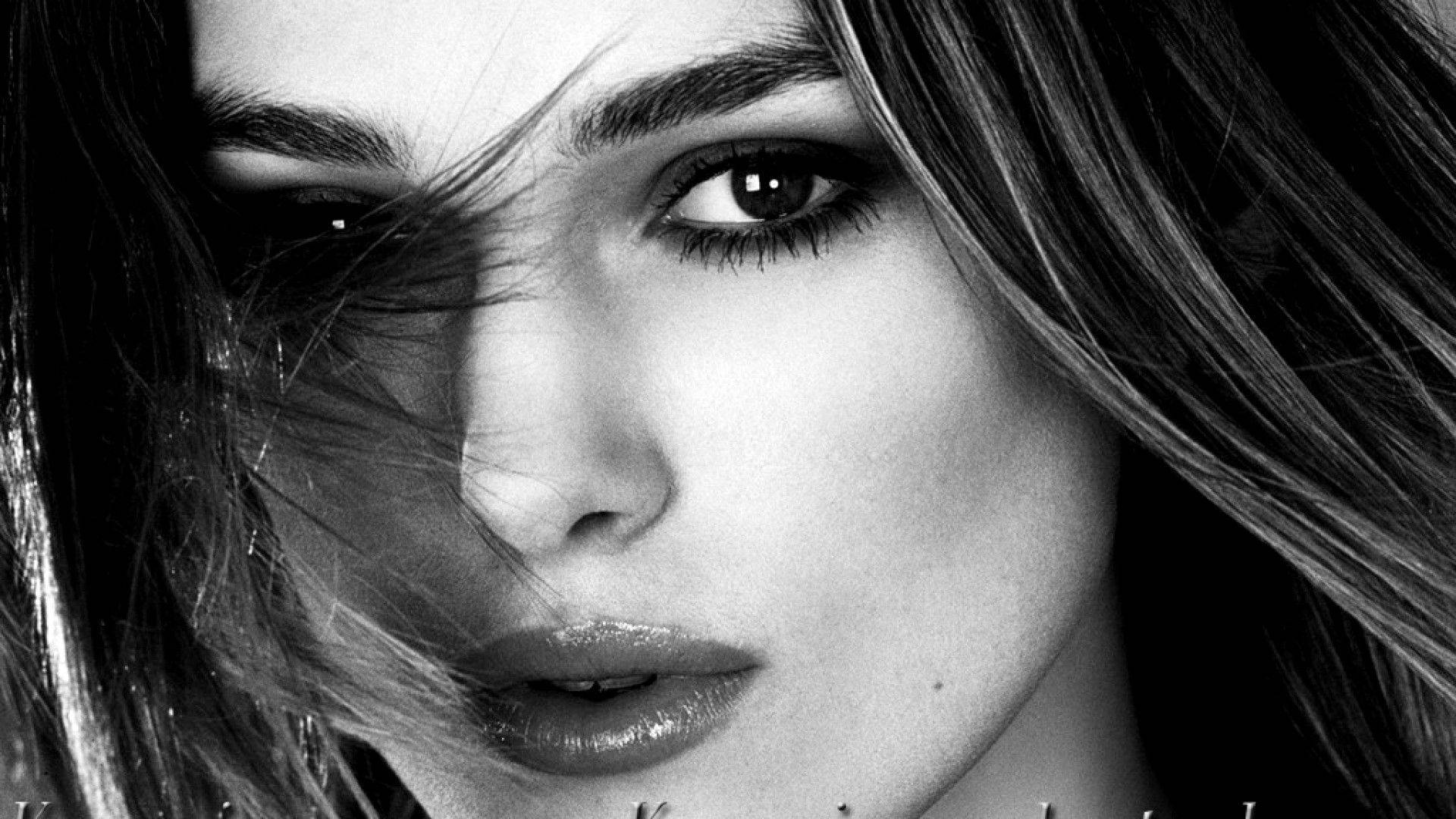 Keira Knightley 桌布 壁紙 — 一個引人注目的黑白特寫，女人的臉被風吹亂的頭髮部分遮住了眼睛。