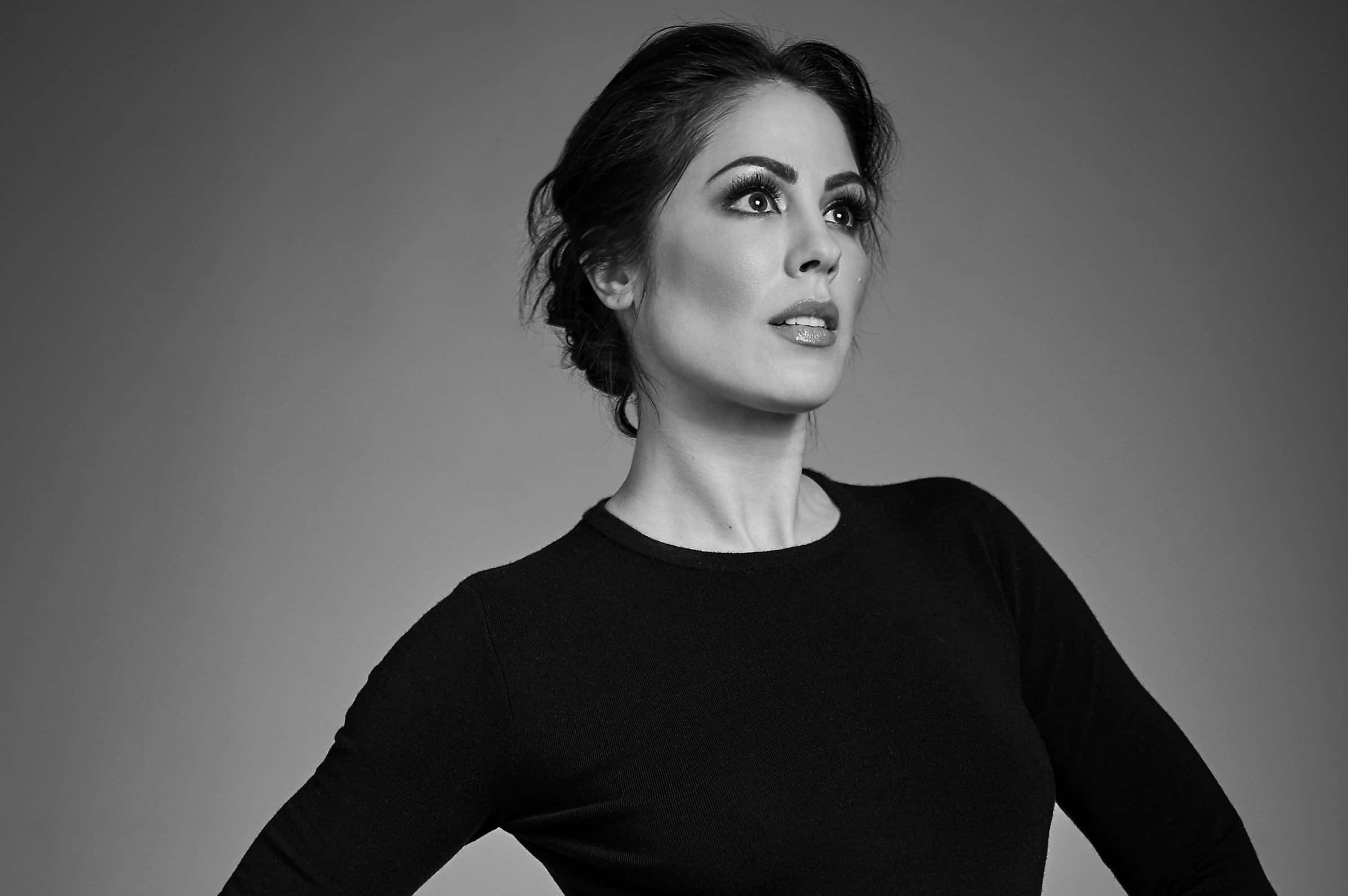 Michelle Borth 桌布 壁紙 — 一個引人注目的黑白肖像，一位化著戲劇性妝容的女性在純灰色背景下向上凝視。