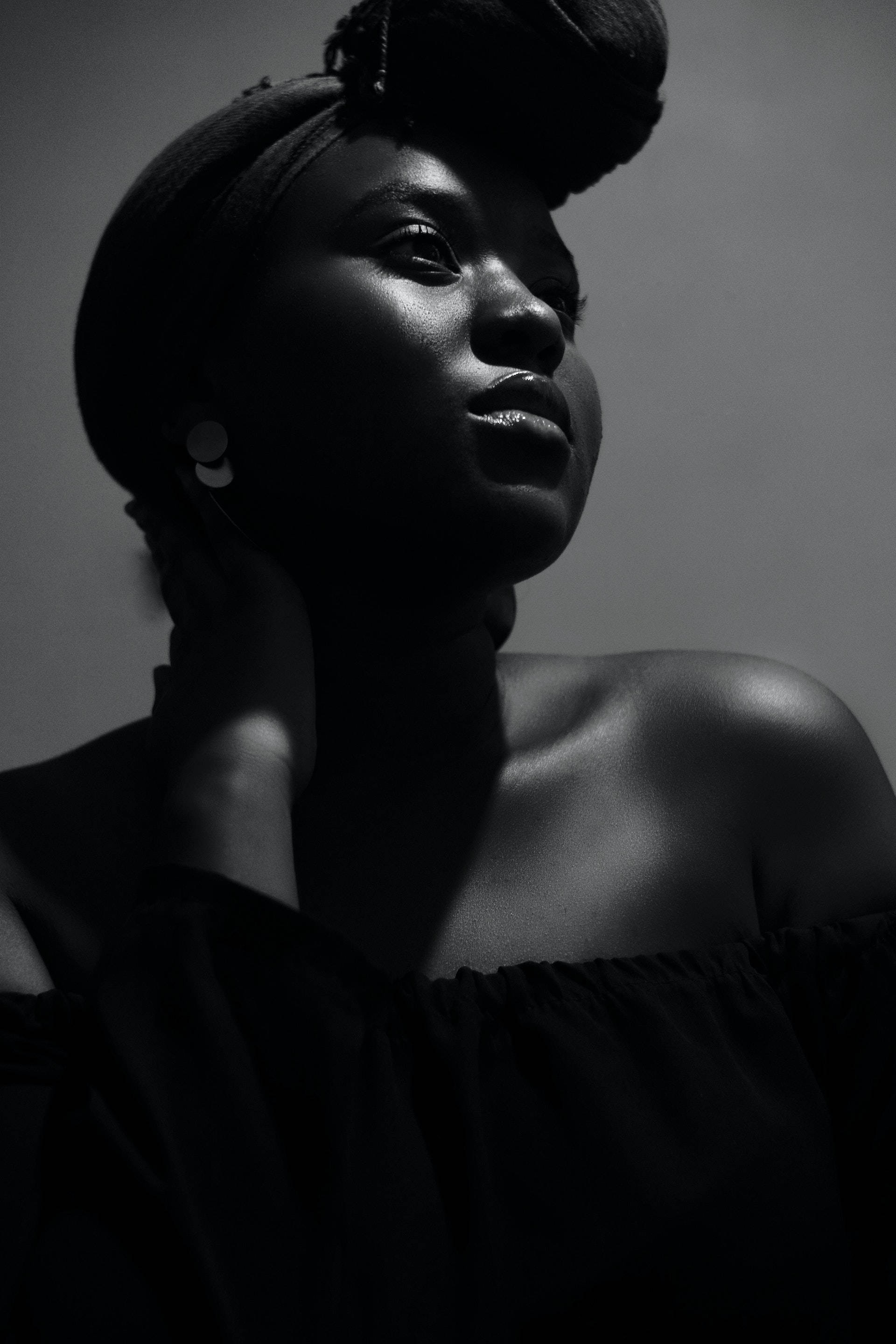 Black Girl 桌布 壁紙 — 一個引人注目的黑白肖像，一位戴著頭巾的女性向上凝視，戲劇性的燈光突顯了她的臉部和肩膀。