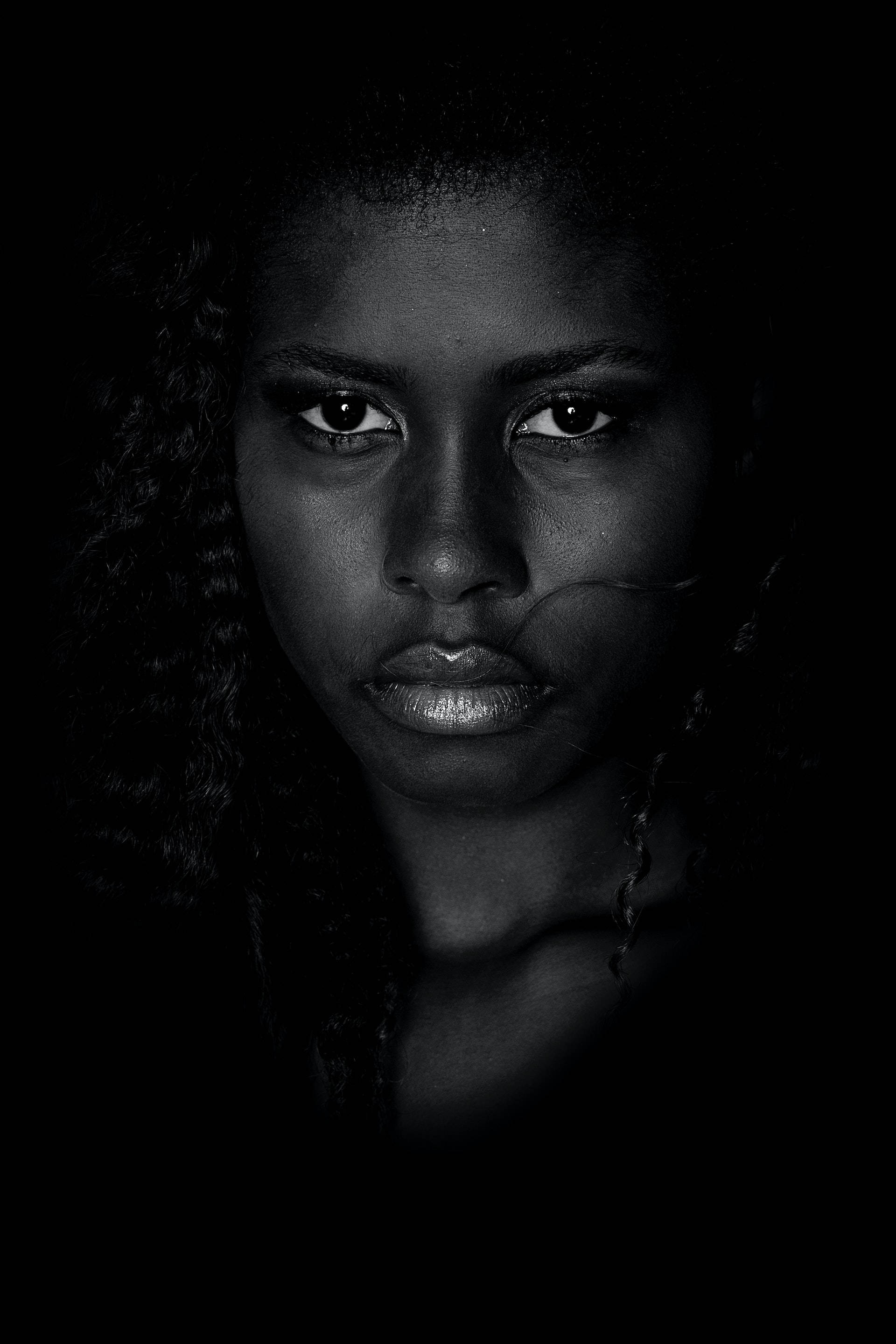Black Girl 桌布 壁紙 — 一個引人注目的黑白肖像，一位擁有強烈眼神和金屬嘴唇的女性，背景為深色。