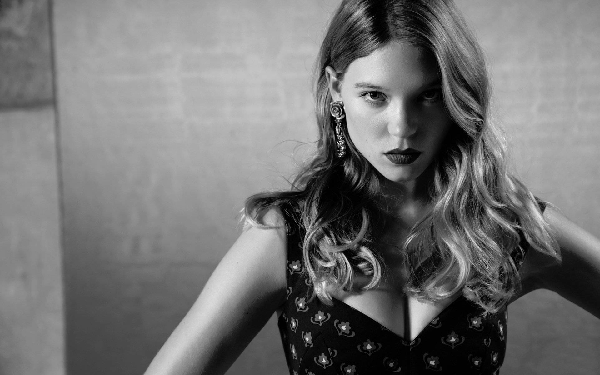Lea Seydoux 桌布 壁紙 — 一個引人注目的黑白肖像，一位波浪髮和鮮豔口紅的女性，強烈地凝視著相機。