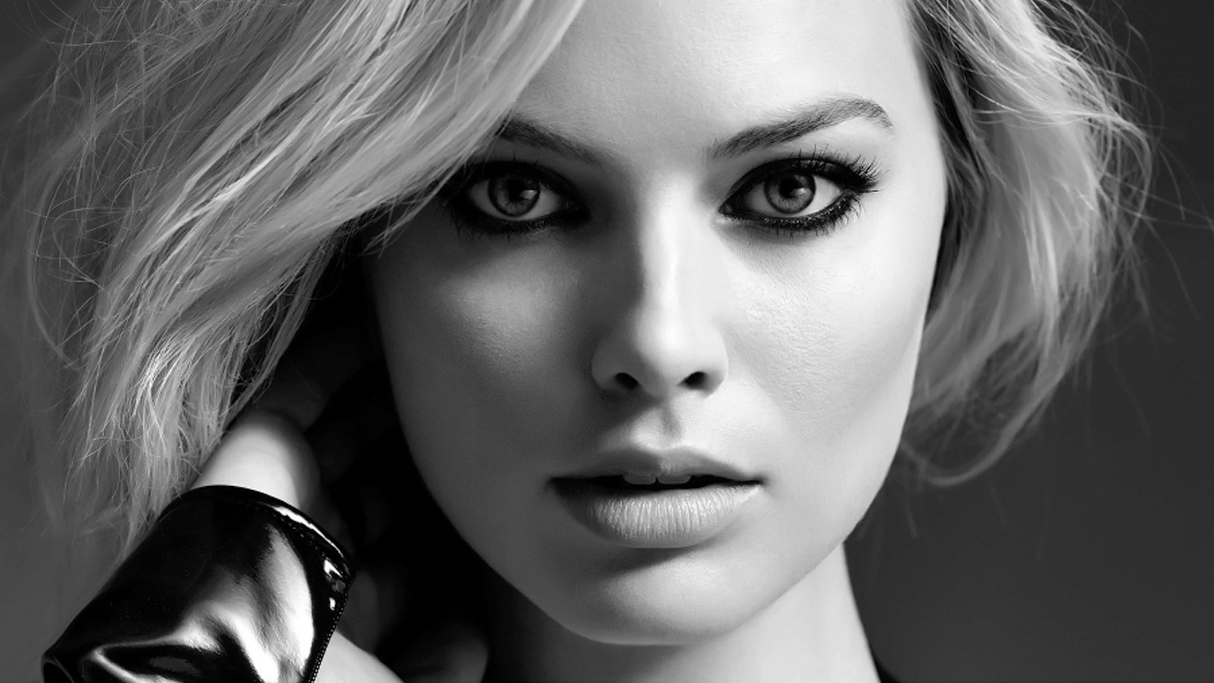 Black And White Celebrity 桌布 壁紙 — 一個引人注目的黑白肖像，一位眼神強烈、金髮的女性，手靠近臉部。