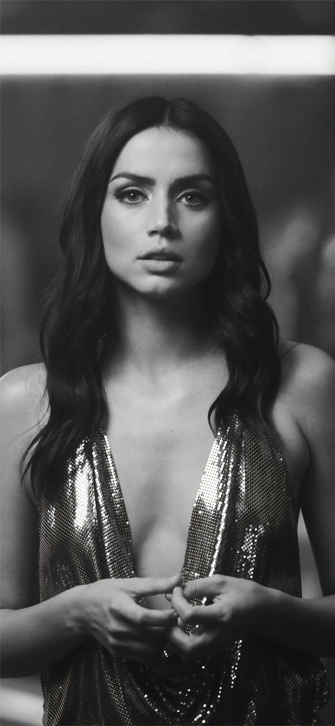 ana de armas 桌布 壁紙 — 一個引人注目的黑白肖像，一位身穿閃亮連衣裙的女性雙手交握在胸前。