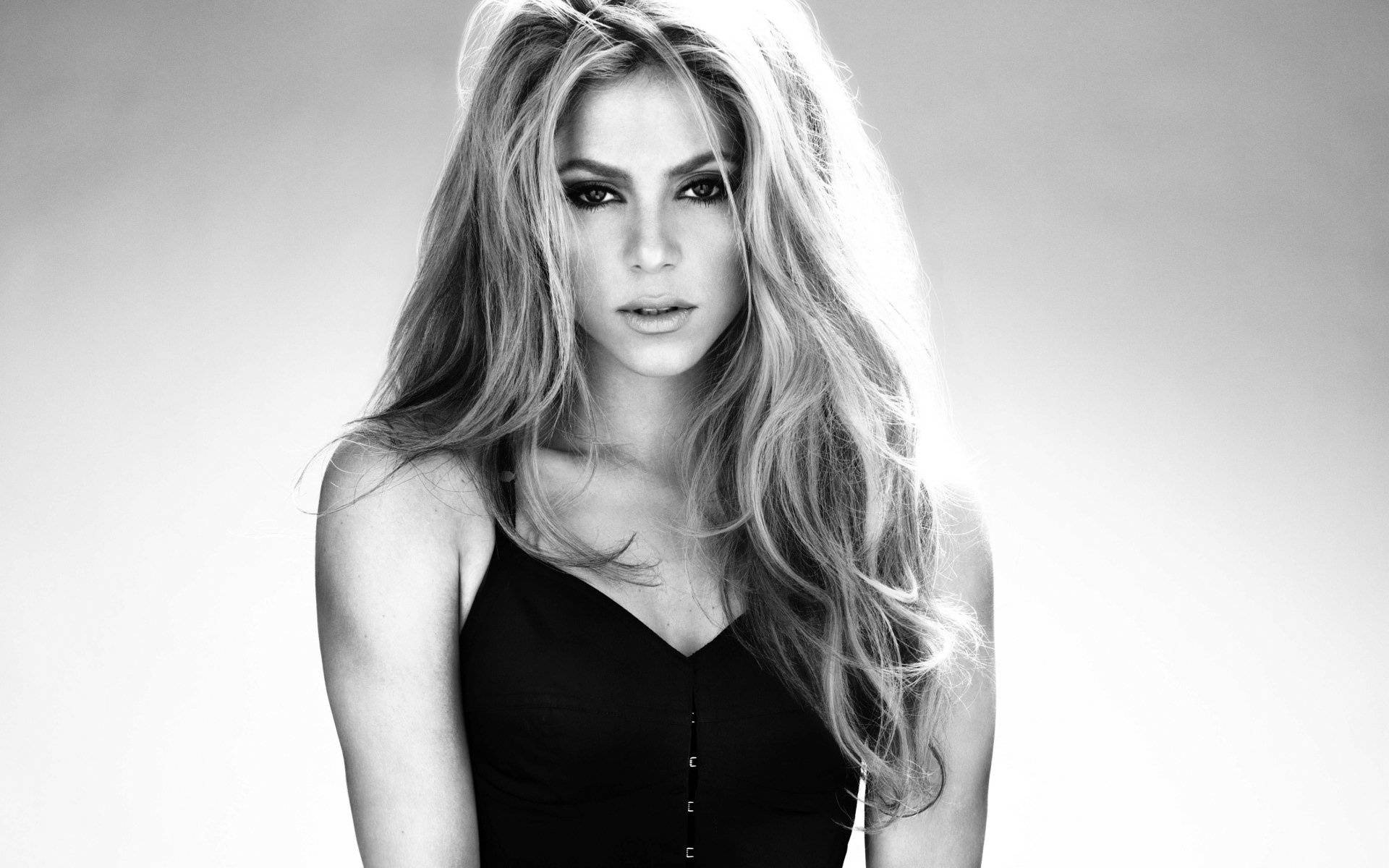 Shakira 桌布 壁紙 — 一個引人注目的黑白肖像，一位長髮飄逸的女性直視鏡頭。