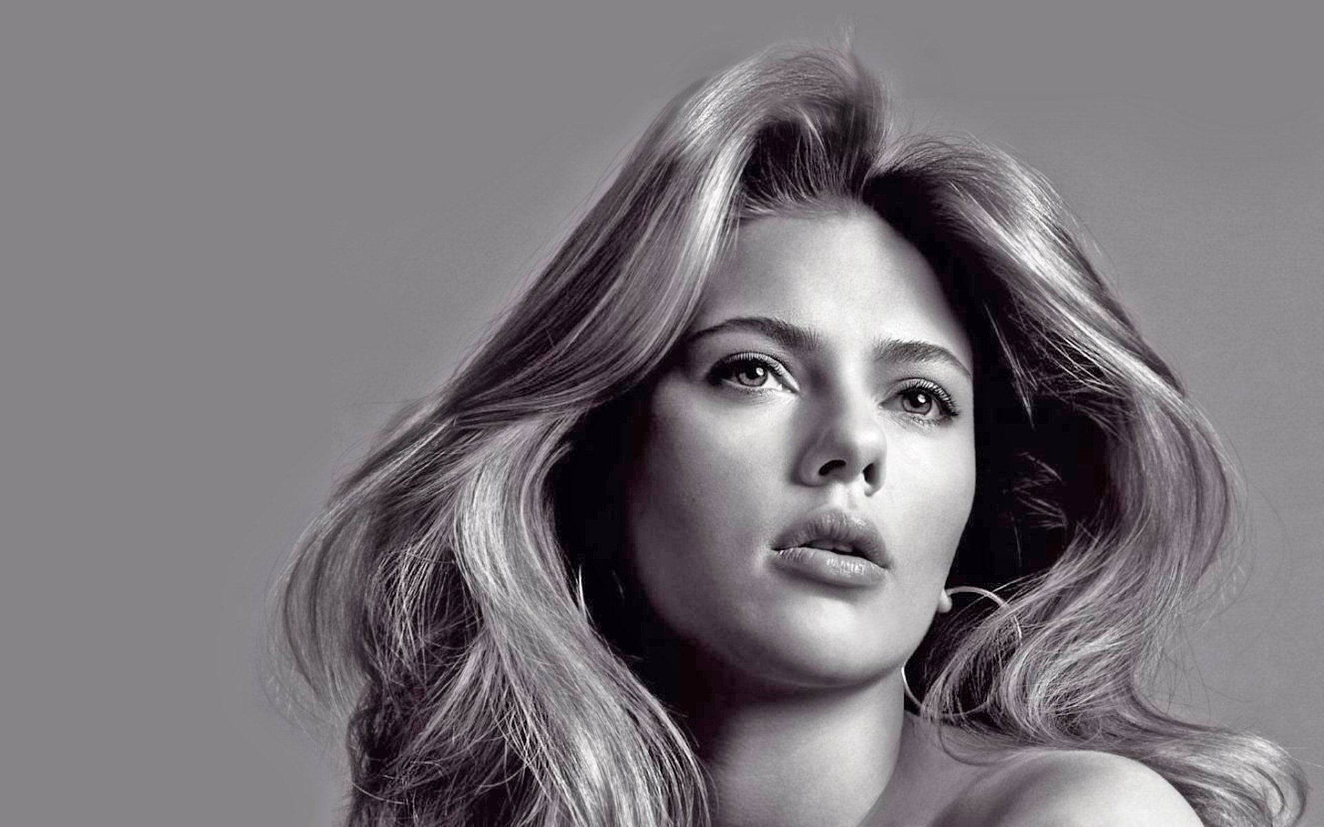 Scarlett 桌布 壁紙 — 一個引人注目的黑白肖像，一位長髮飄逸的女性在純灰色背景下若有所思地凝視。