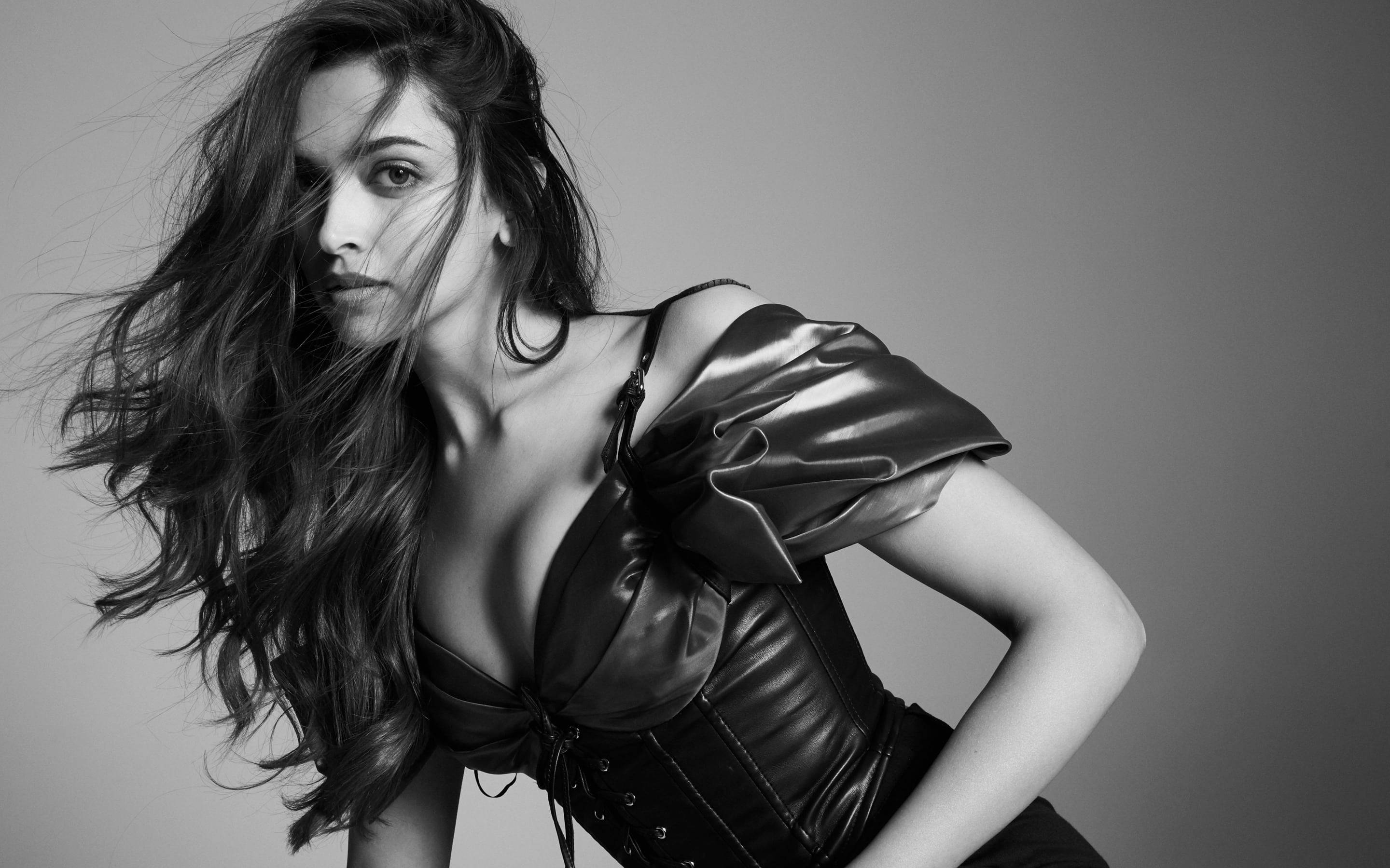 Deepika 桌布 壁紙 — 一個引人注目的黑白肖像，一位頭髮被風吹亂的女性穿著戲劇性的束身衣裝，背景簡潔。