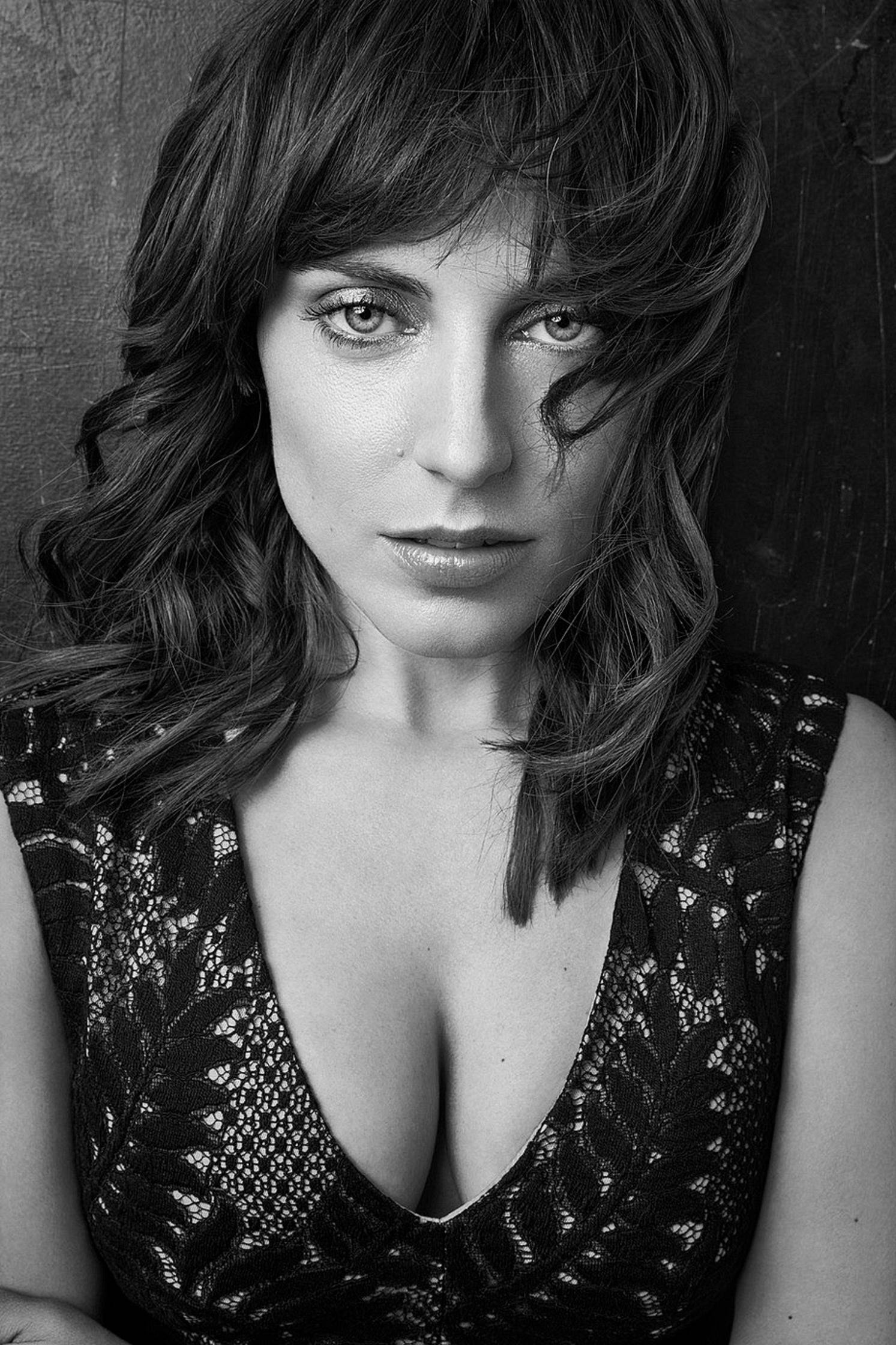 Antje Traue 桌布 壁紙 — 一個引人注目的黑白肖像，一位頭髮蓬亂、眼神強烈的女性穿著蕾絲上衣。