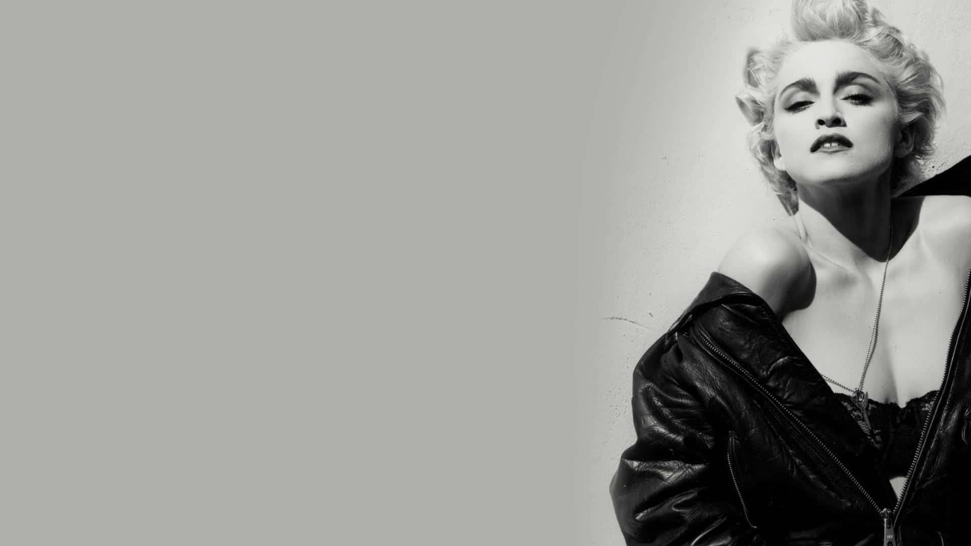 Madonna 桌布 壁紙 — 一個引人注目的黑白肖像，一位頭髮蓬亂的女人穿著敞開的皮夾克，靠著素牆。