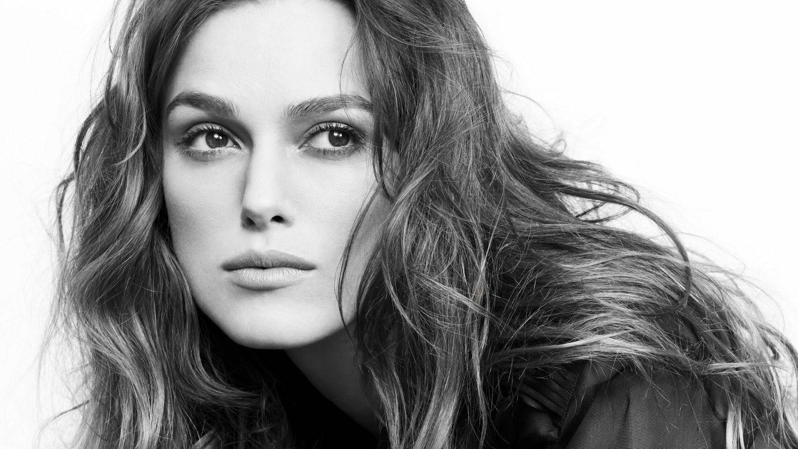 Keira Knightley 桌布 壁紙 — 一個引人注目的黑白肖像，一位頭髮被風吹拂的女人直視鏡頭。
