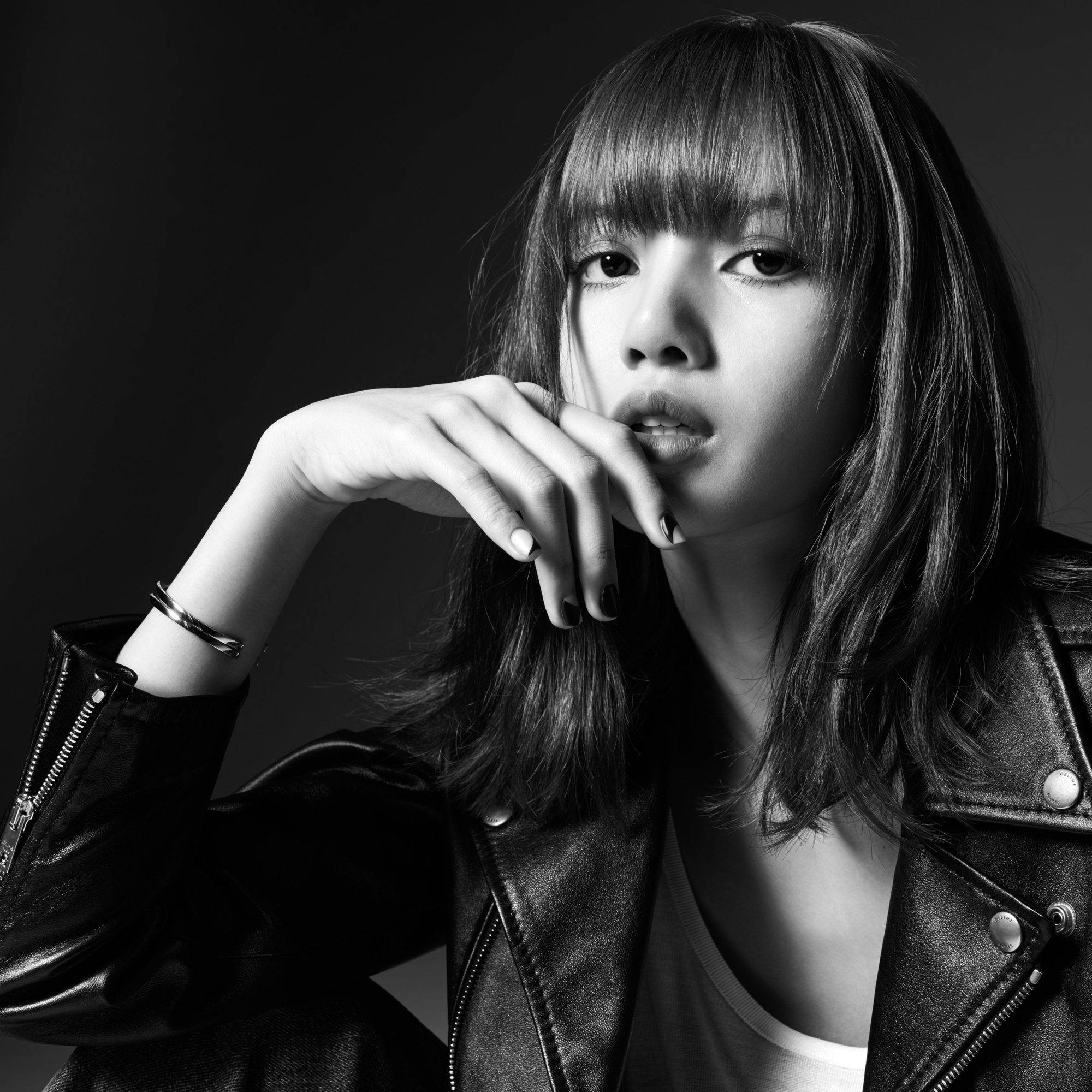 Lalisa 桌布 壁紙 — 一個引人注目的黑白肖像，一個穿著皮夾克的女人，手靠近嘴唇，背景黑暗。