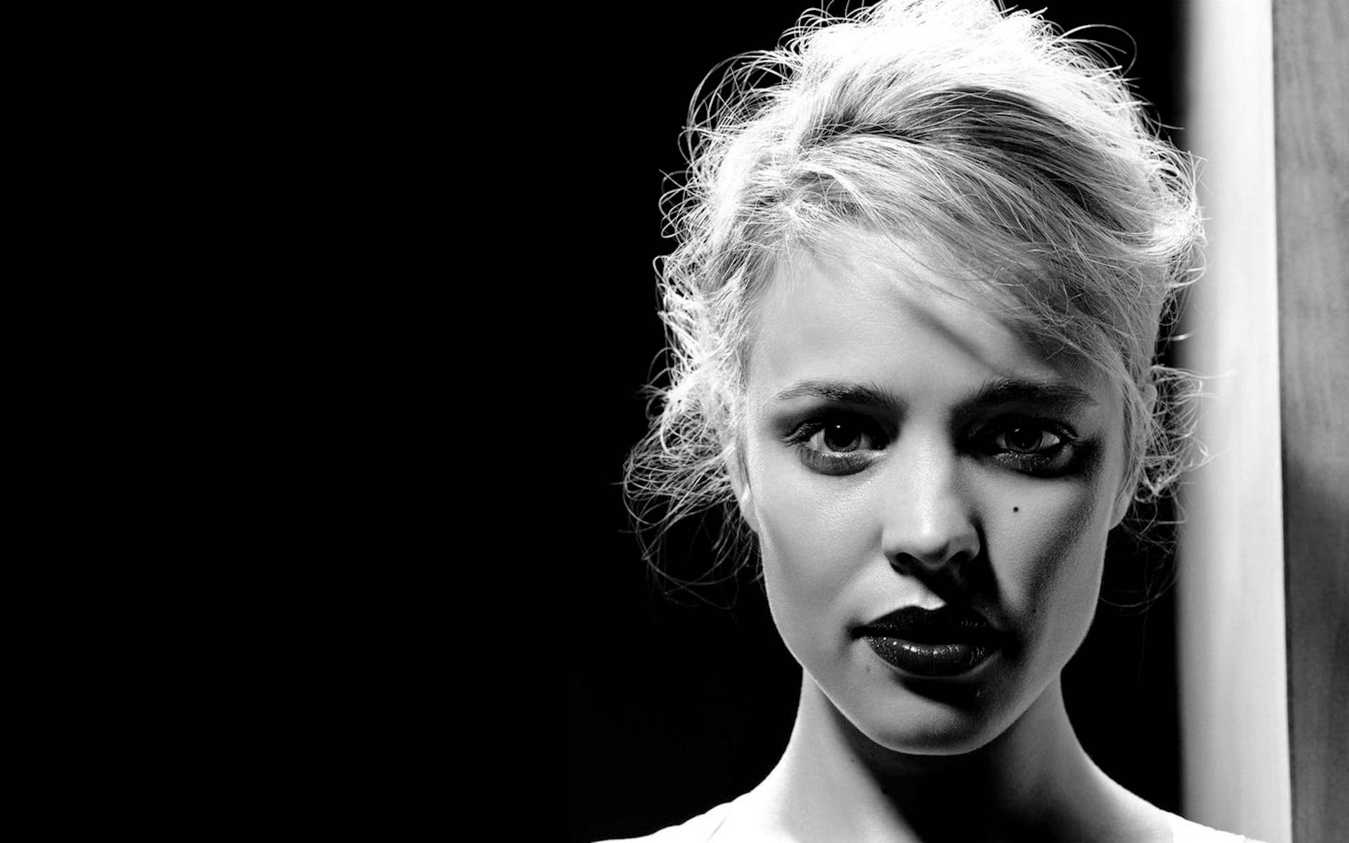 Rachel Mcadams 桌布 壁紙 — 一個引人注目的黑白肖像，一個金髮凌亂、眼神強烈的女性，背景為深色。