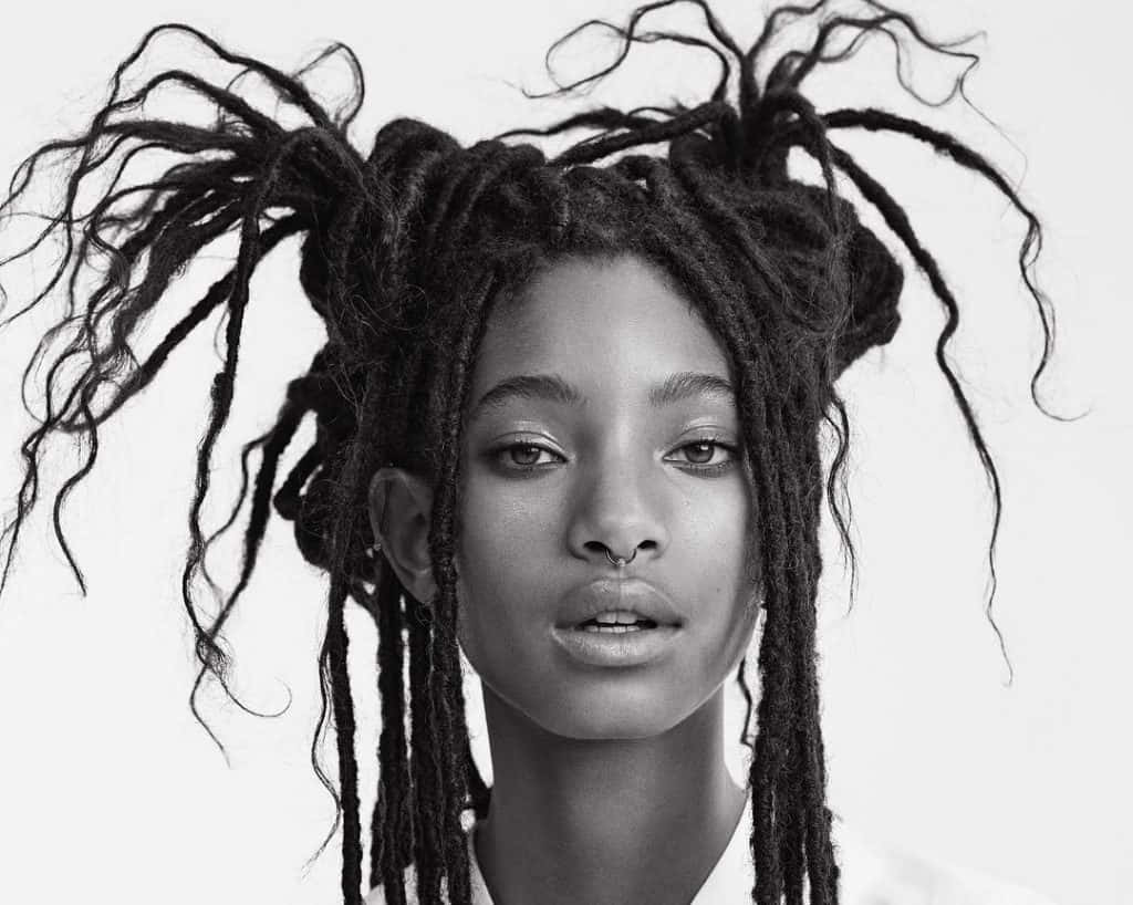 Black And White Celebrity 桌布 壁紙 — 一個引人注目的黑白肖像，一名擁有豐盈辮子頭和鼻環的女性直視鏡頭。