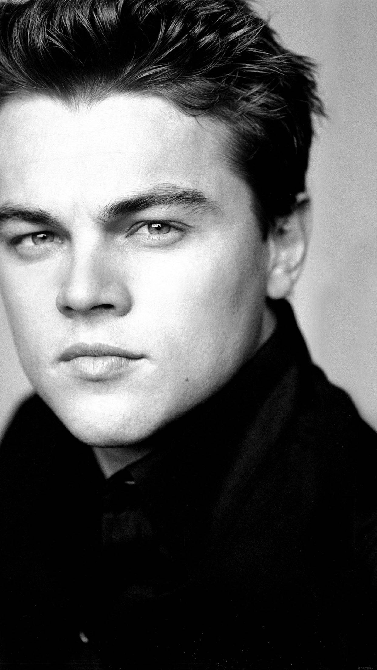 Dicaprio 桌布 壁紙 — 一個引人注目的黑白肖像，年輕男子眼神強烈，頭髮有紋理，背景簡單。