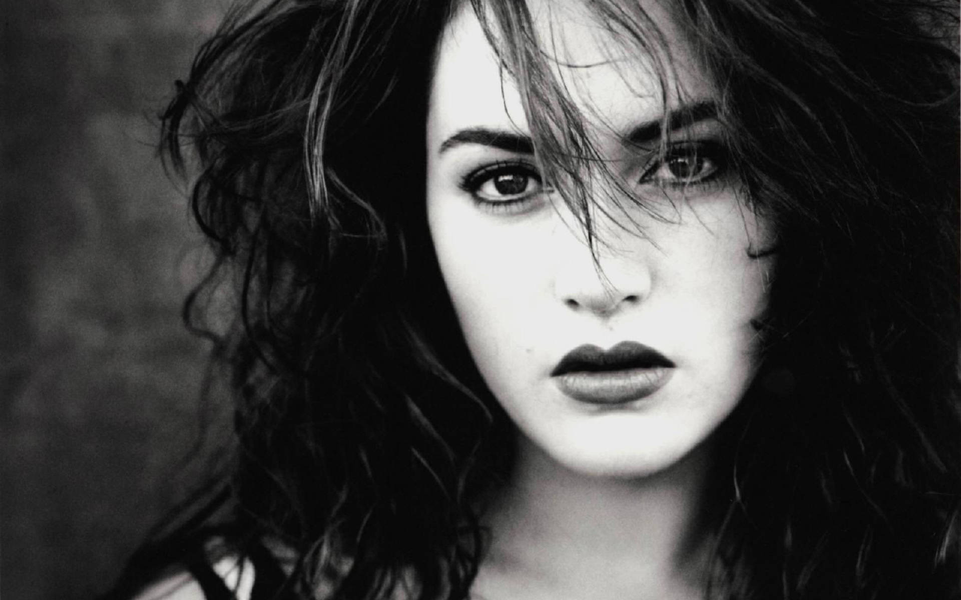 Kate Winslet 桌布 壁紙 — 一個引人注目的黑白肖像，描繪一位頭髮被風吹亂、眼神強烈的女性，直視觀眾。