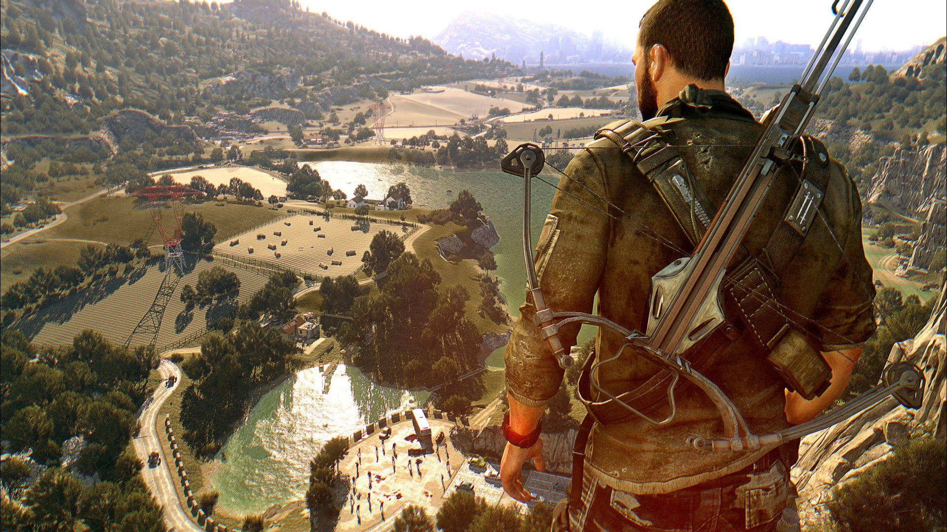 Dying Light 桌布 壁紙 — 一個強壯的弓箭手從岩石懸崖邊俯瞰著一個陽光明媚的山谷，山谷中有蜿蜒的道路、湖泊和遠處的山脈。
