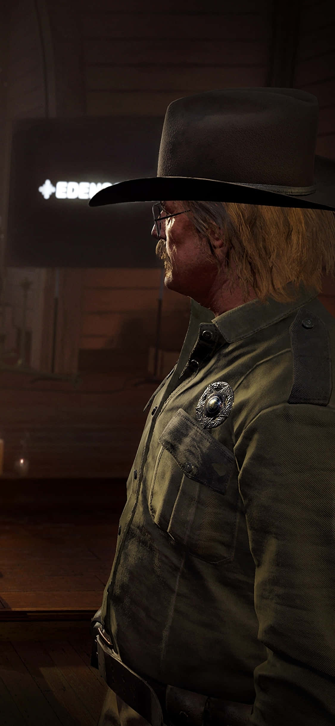 iPhone Xs Far Cry 5 桌布 壁紙 — 一個強壯的牛仔警長，穿著破舊的制服和帽子，站在燈光昏暗的沙龍裡，身後有一個發光的招牌。