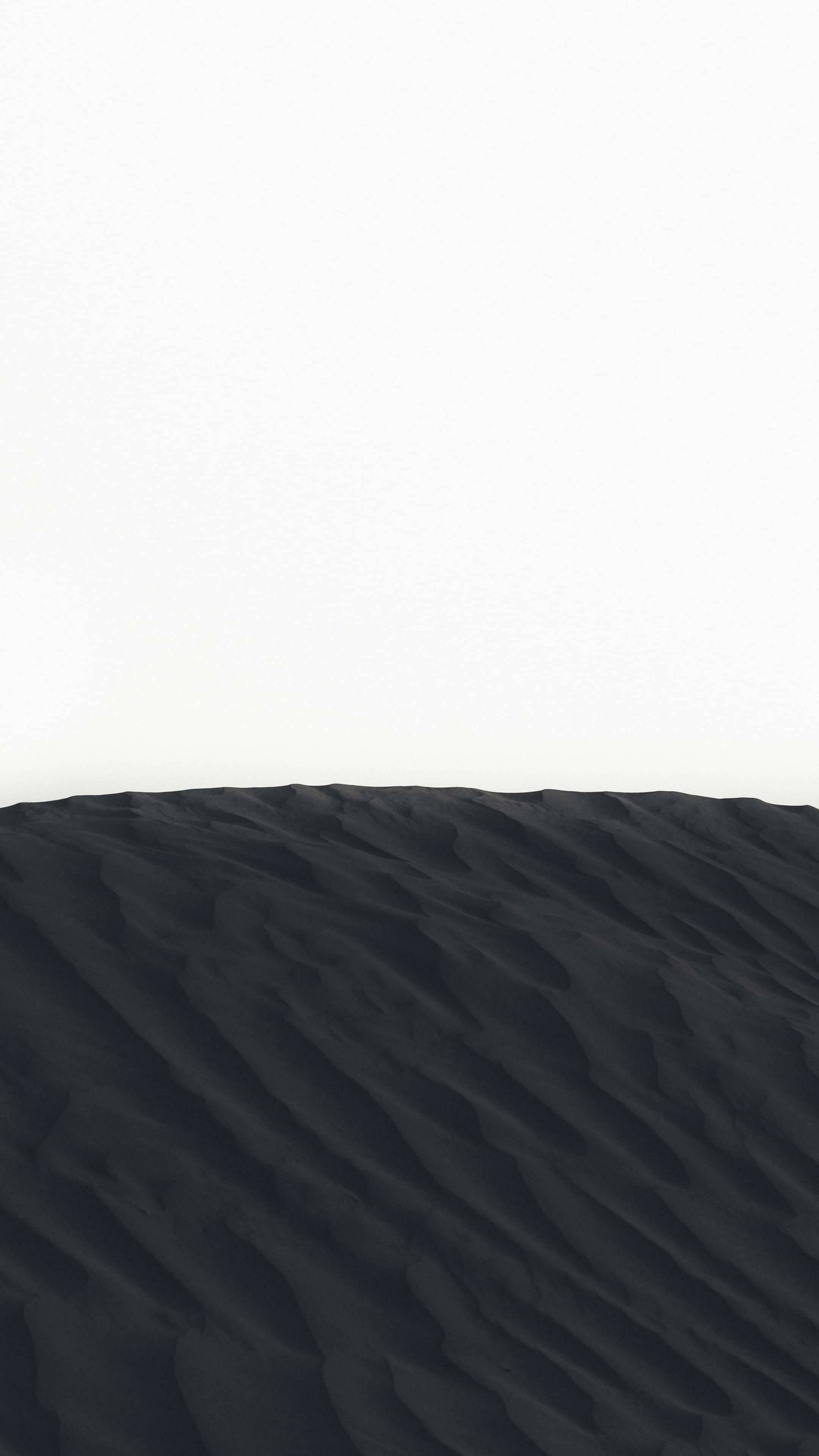 Minimalist Phone 桌布 壁紙 — 一個強烈的極簡主義景觀，黑暗的波紋沙子在水平線上與明亮的白色天空相遇。