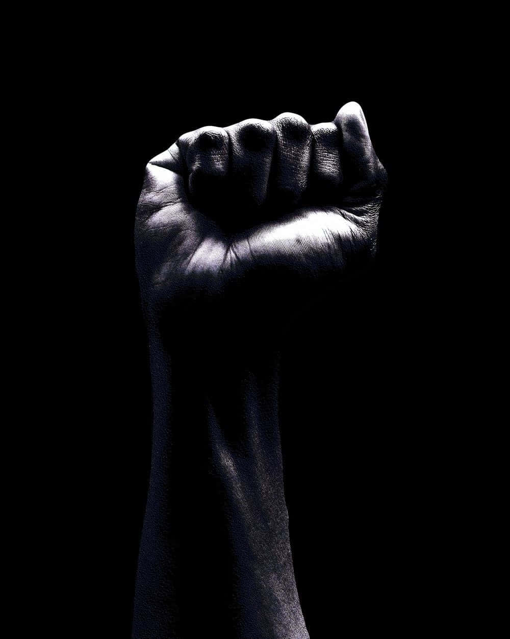 Empowerment 桌布 壁紙 — 一個強而有力的舉起拳頭，在純黑背景上被照亮，象徵抵抗與團結。