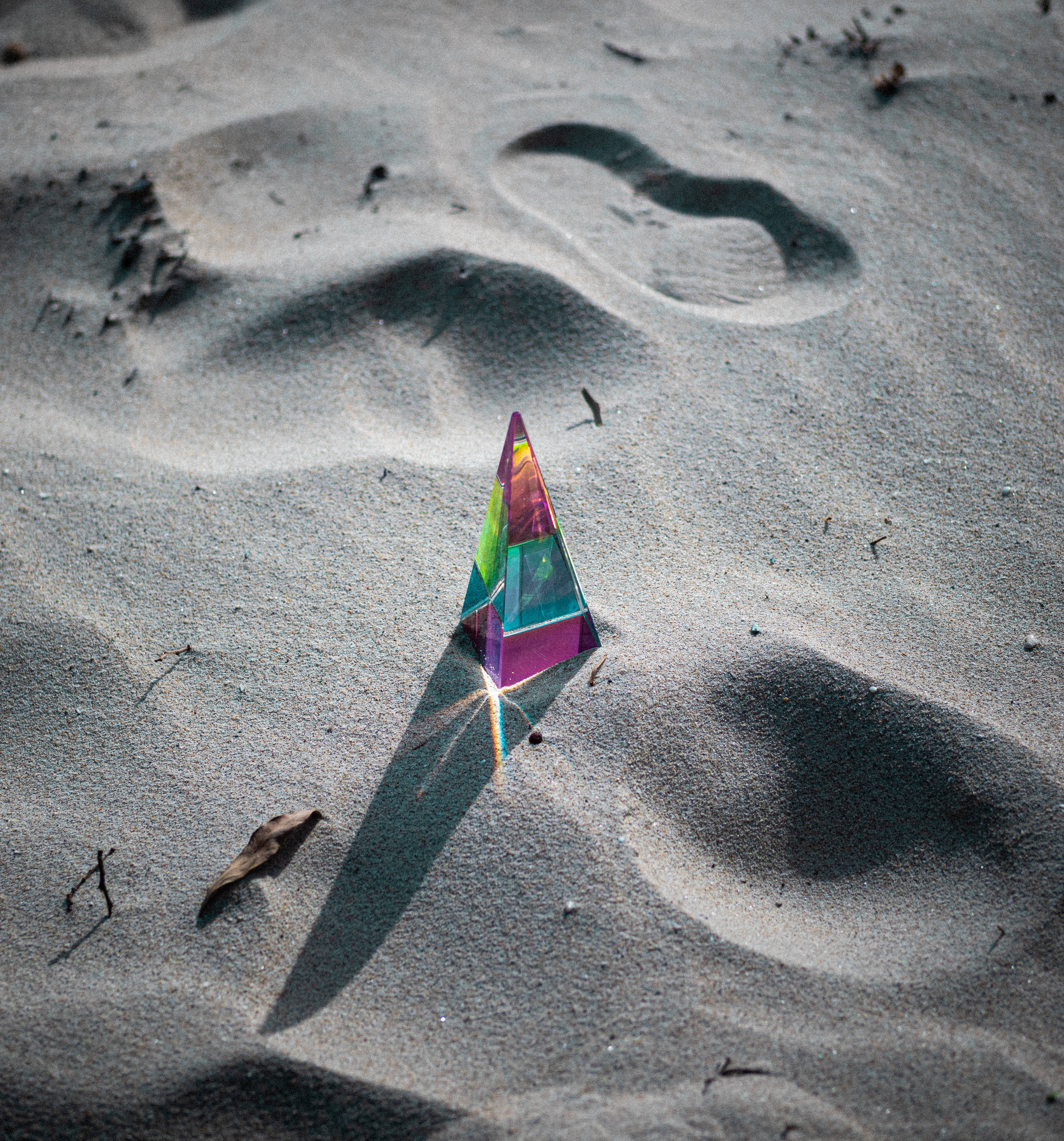 Prism 桌布 壁紙 — 一個彩色玻璃金字塔在紋理沙子上折射陽光，投射出充滿活力的星形陰影。