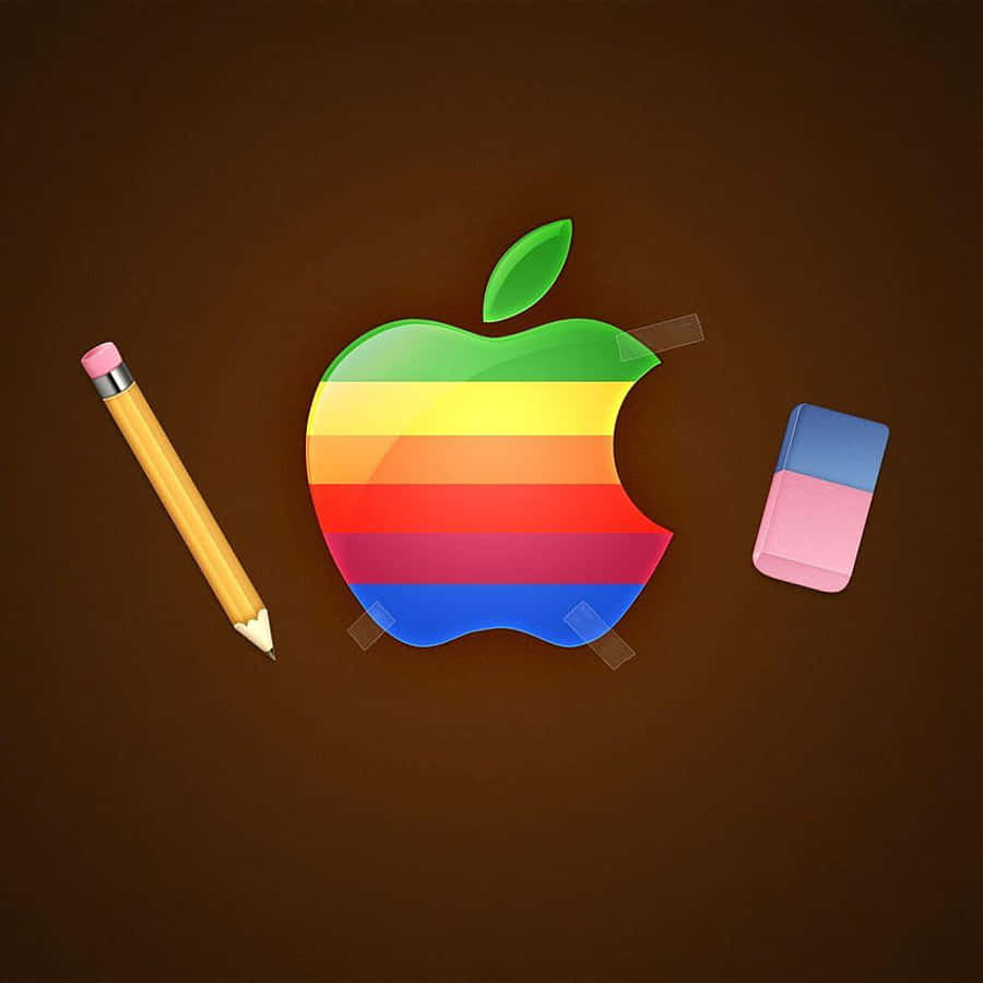 桌布 壁紙 — 一個彩虹條紋的Apple標誌用膠帶貼在棕色表面上，附近有一支黃色鉛筆和粉紅色橡皮擦。