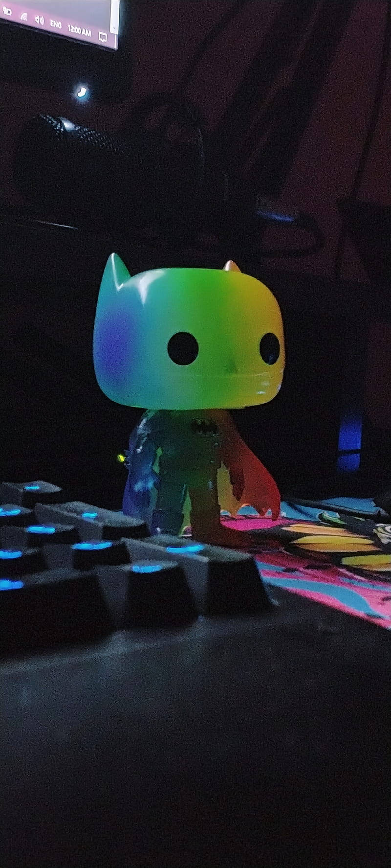 蝙蝠俠 桌布 壁紙 — 一個彩虹照亮的蝙蝠俠Funko Pop坐在一個黑暗房間中帶有彩色點綴的發光鍵盤上。
