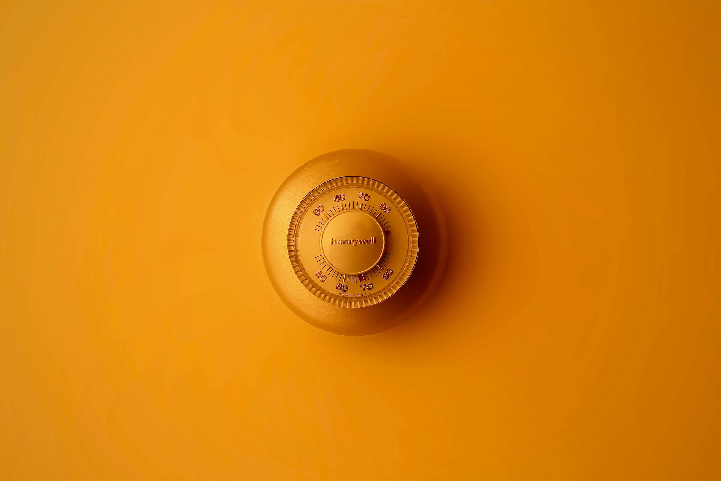 mechanical 桌布 壁紙 — 一個復古Honeywell恆溫器置於溫暖漸層橙色牆壁中央，光線柔和。