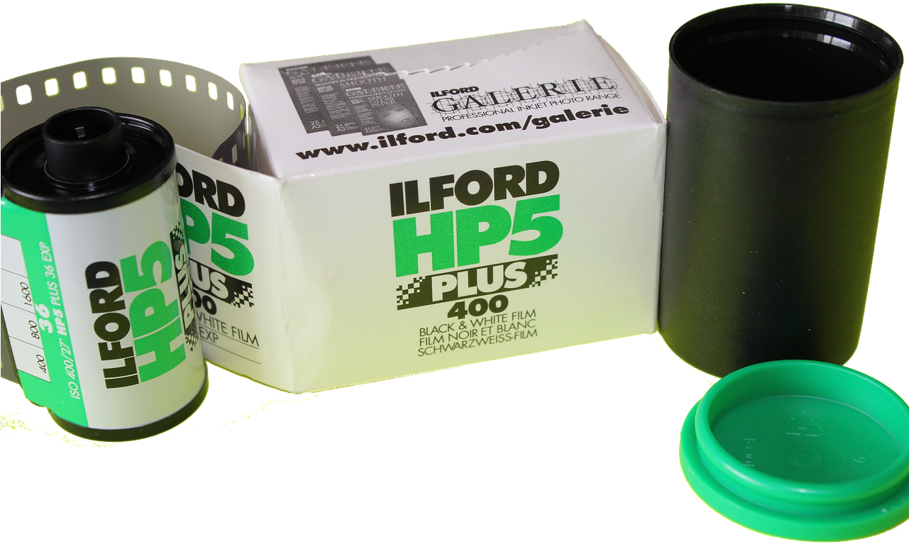 電影 桌布 壁紙 — 一個復古Ilford HP5 Plus 400黑白底片罐連同其盒子和一個綠色底片容器蓋子，放在純黑色背景前。