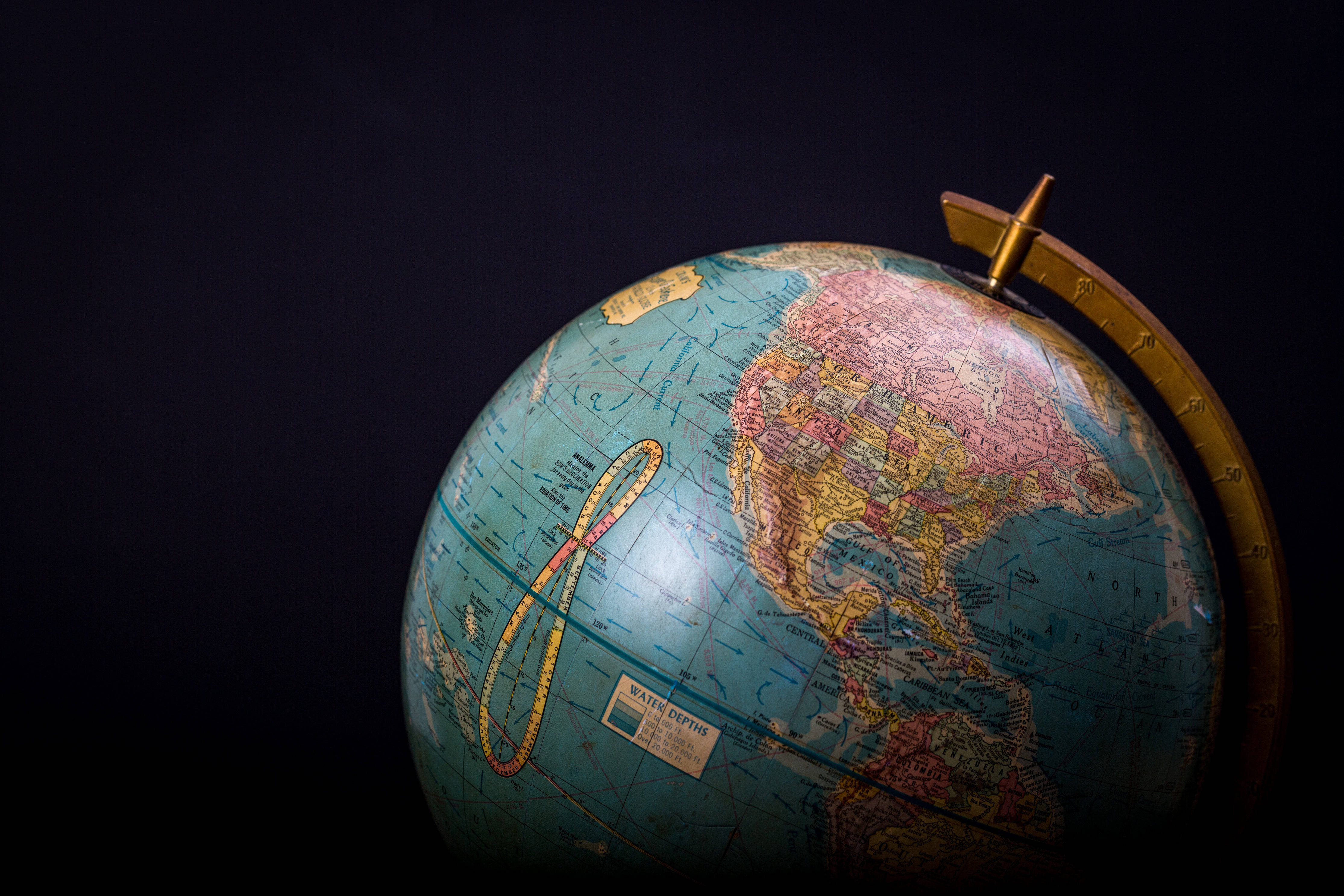 Globe Map 桌布 壁紙 — 一個復古地球儀，北美洲被金色捲尺在深色背景上突出顯示。