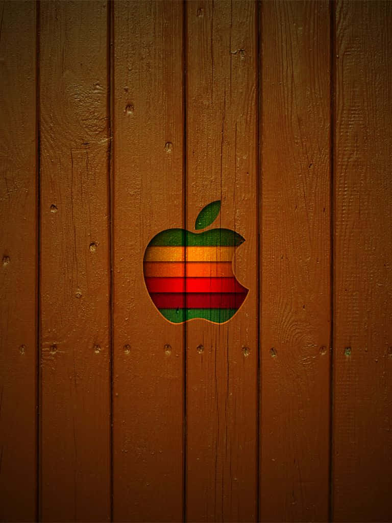 Apple 4K 桌布 壁紙 — 一個復古彩虹Apple標誌，切割在溫暖的棕色木板上，帶有可見的木紋和節疤。