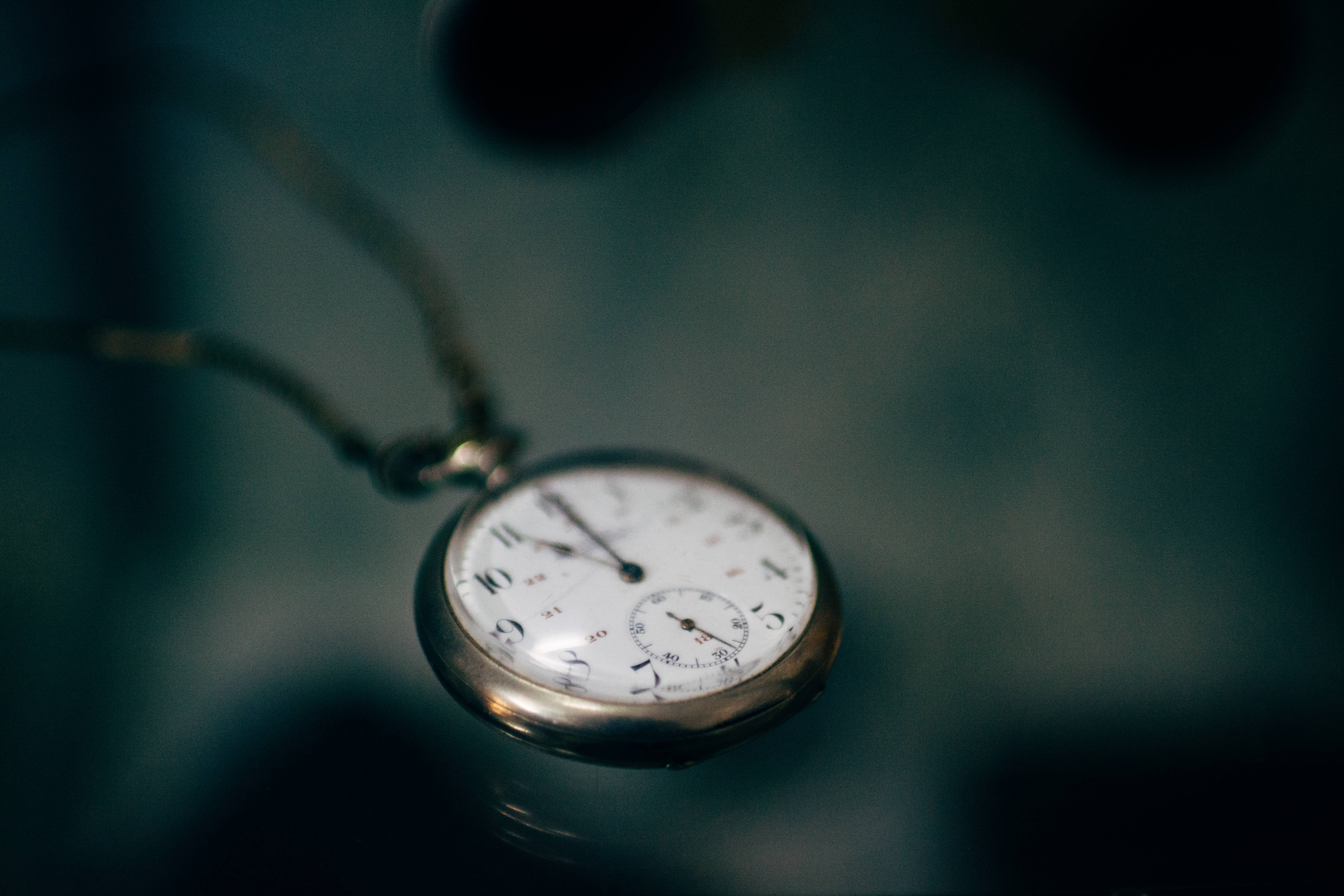 sexy time 桌布 壁紙 — 一個復古懷錶，白色錶面，銀色外殼，懸掛在深藍綠色模糊背景上。