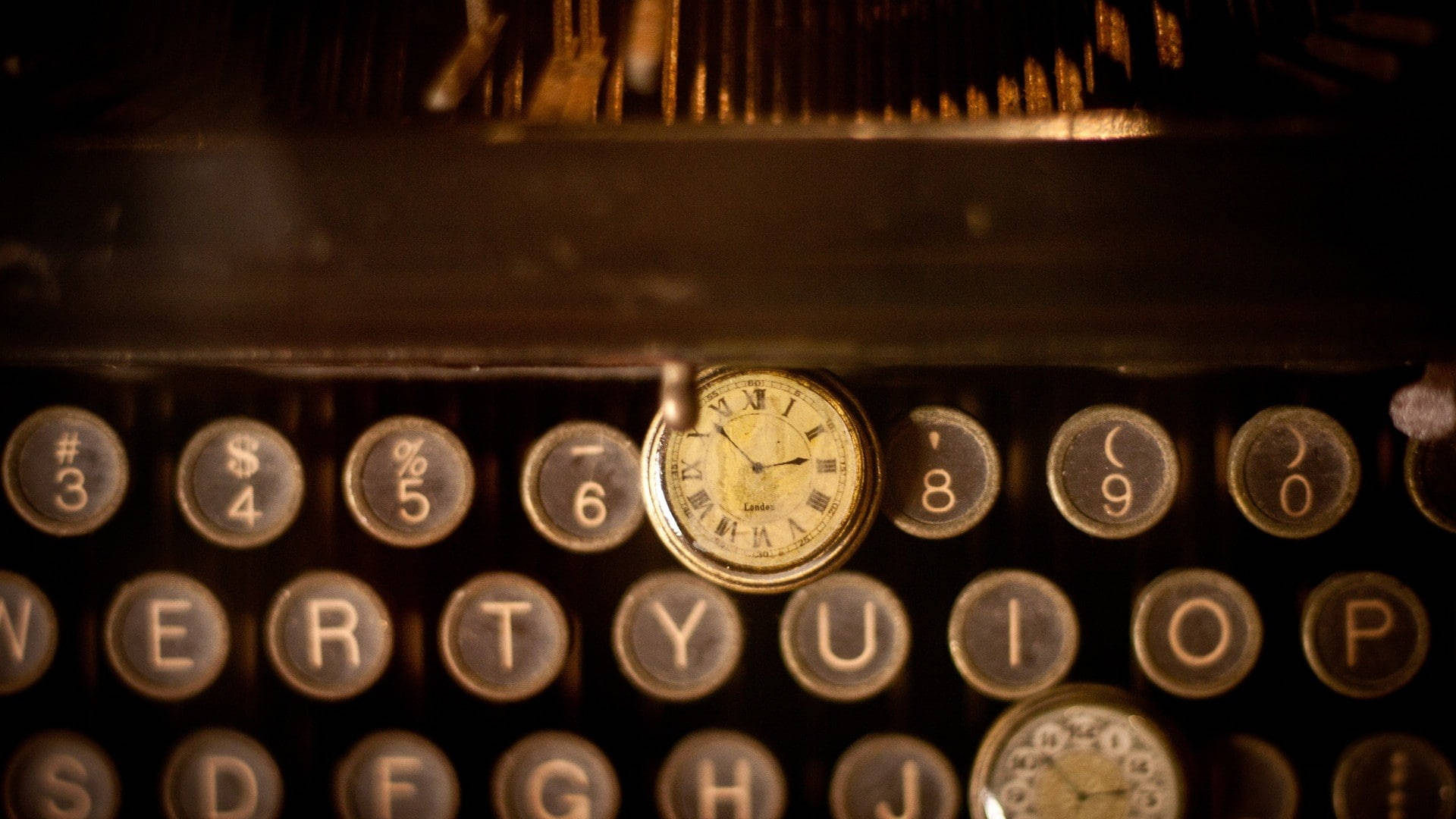 Clock 桌布 壁紙 — 一個復古打字機鍵盤沐浴在溫暖的金色光芒中，一個小型指針時鐘藏在按鍵之間。