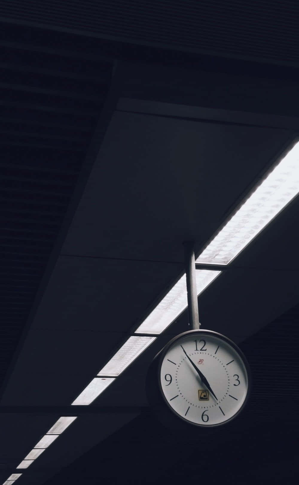Time 桌布 壁紙 — 一個復古指針時鐘懸掛在天花板下，螢光燈照亮了一個光線昏暗的現代室內空間。