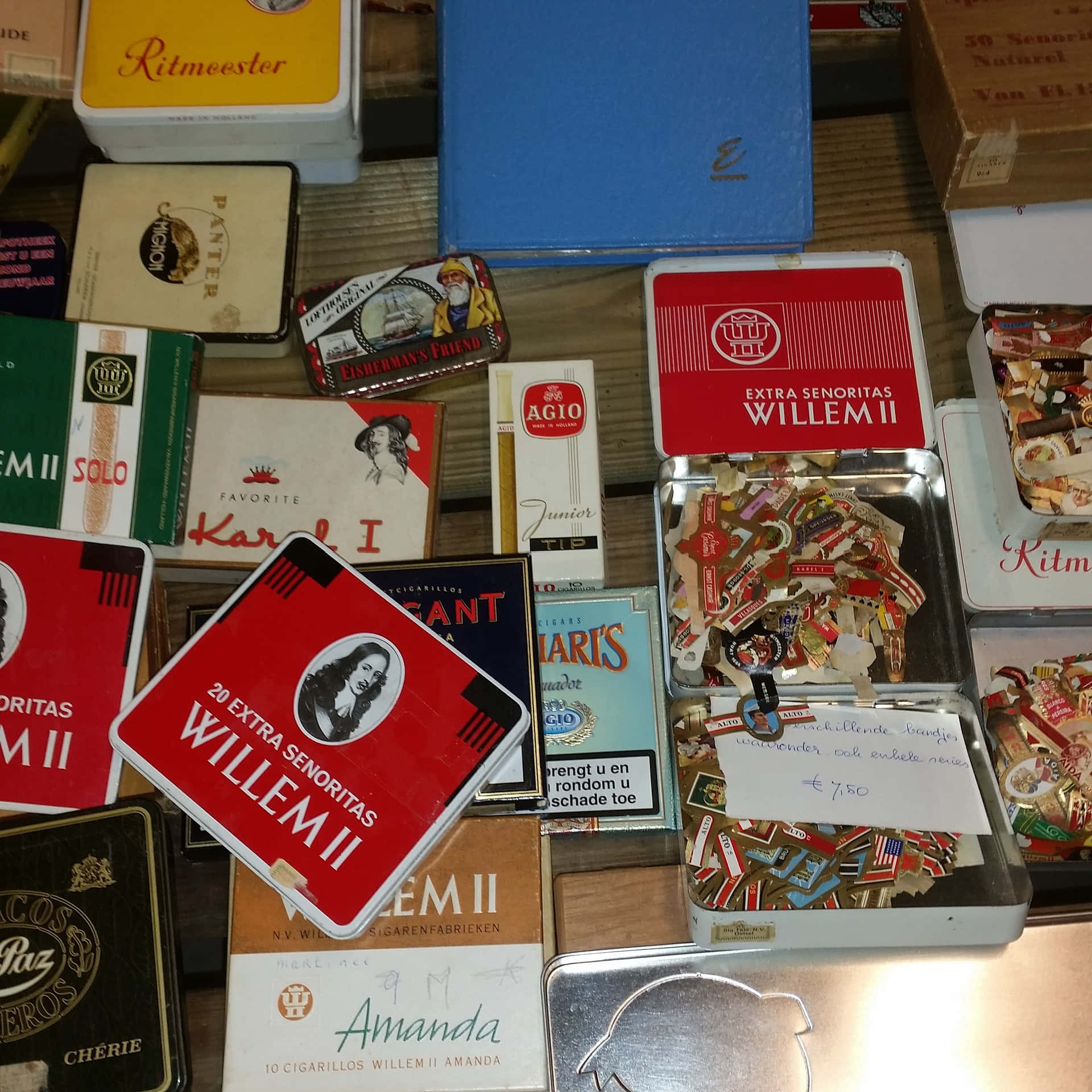 cigarettes 桌布 壁紙 — 一個復古收藏，包括色彩繽紛的煙草罐和煙包，排列在木質表面上，附有價格標籤。