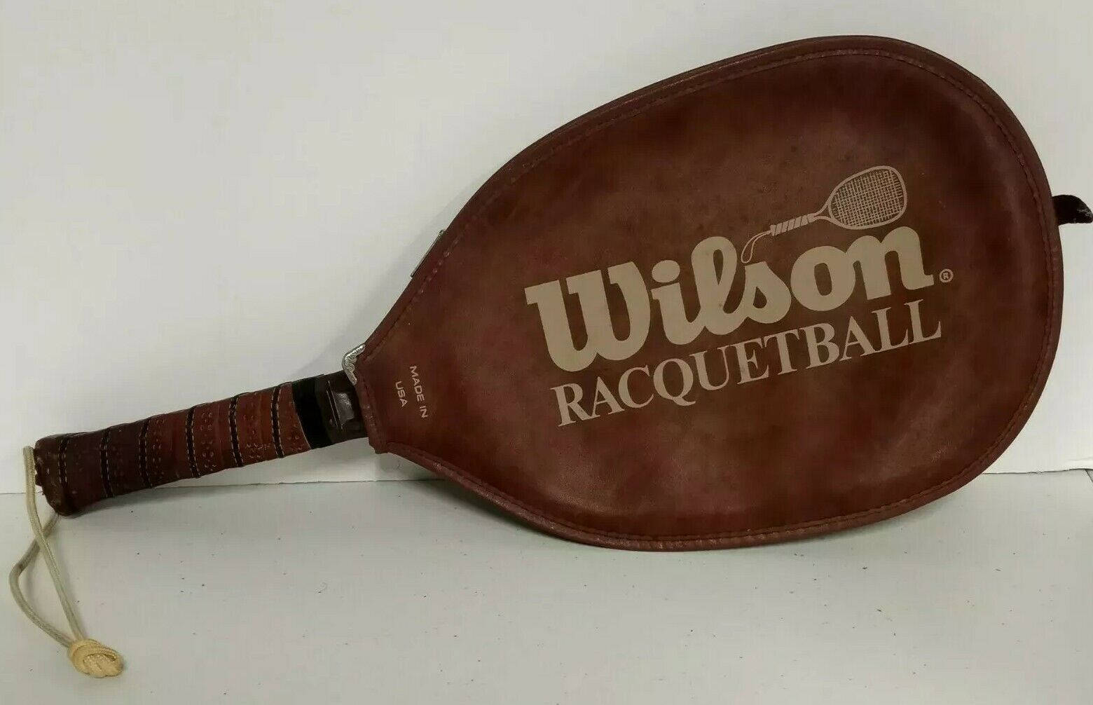 game 桌布 壁紙 — 一個復古棕色皮革 Wilson 壁球拍靠在純白色背景上。
