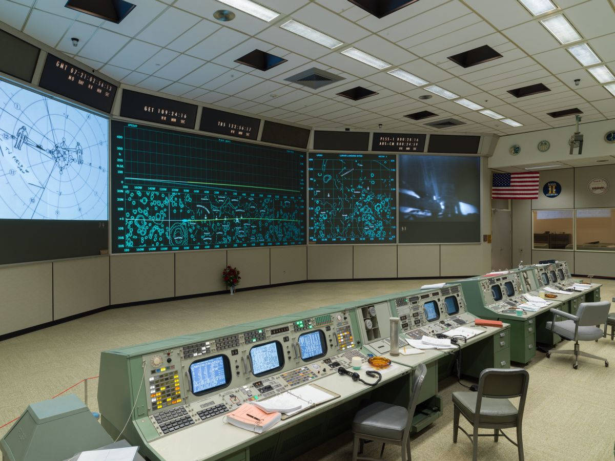 NASA 動態圖片 桌布 壁紙 — 一個復古的NASA任務控制室，配有綠色控制台和發光的藍色螢幕，顯示複雜的數據和雷達地圖。