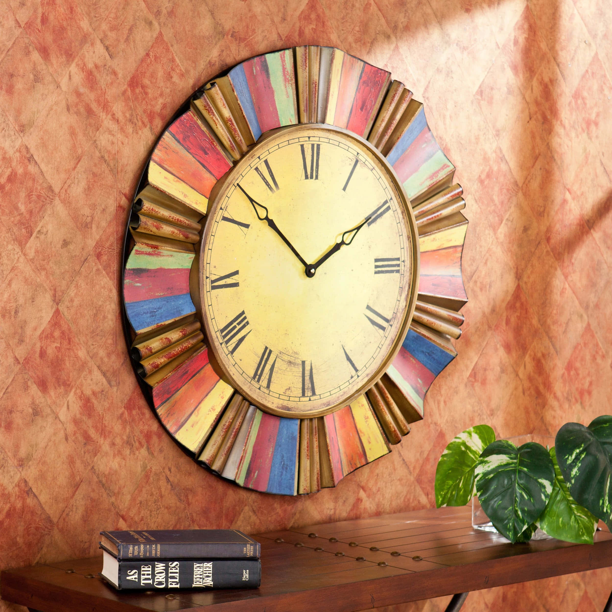 Wall Clock 桌布 壁紙 — 一個復古的太陽爆發時鐘，帶有彩色木製射線，掛在紋理豐富的赤陶牆上，上方是一個木製架子，上面放著書籍和龜背竹植物。