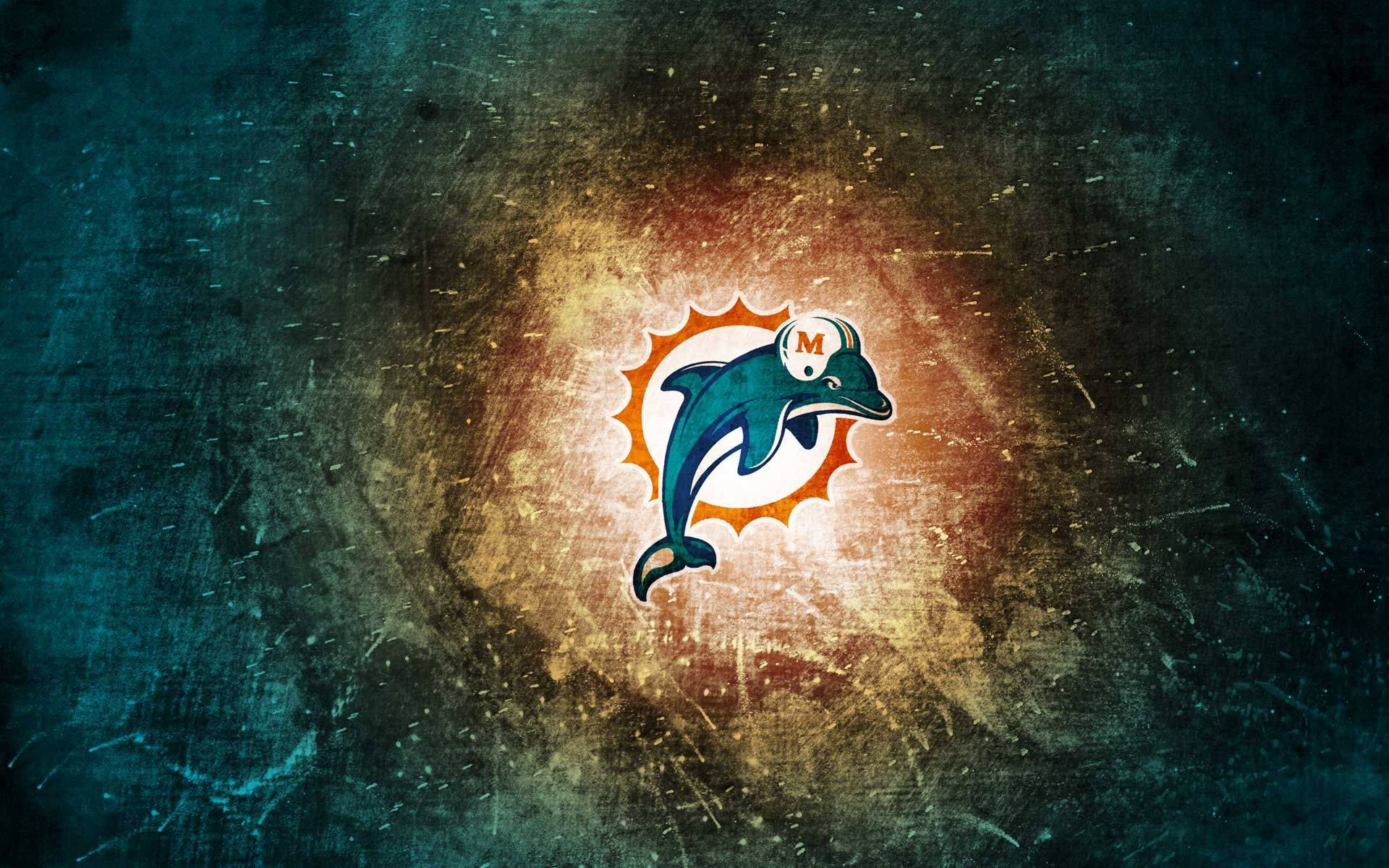 dolphins 桌布 壁紙 — 一個復古的邁阿密海豚標誌在帶有刮痕和斑點的紋理深青色和橙色背景上溫暖地發光。