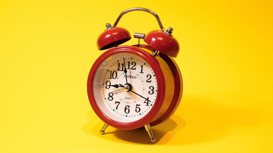 Clock 桌布 壁紙 — 一個復古紅色鬧鐘，帶有雙鈴，位於明亮的黃色背景中央。
