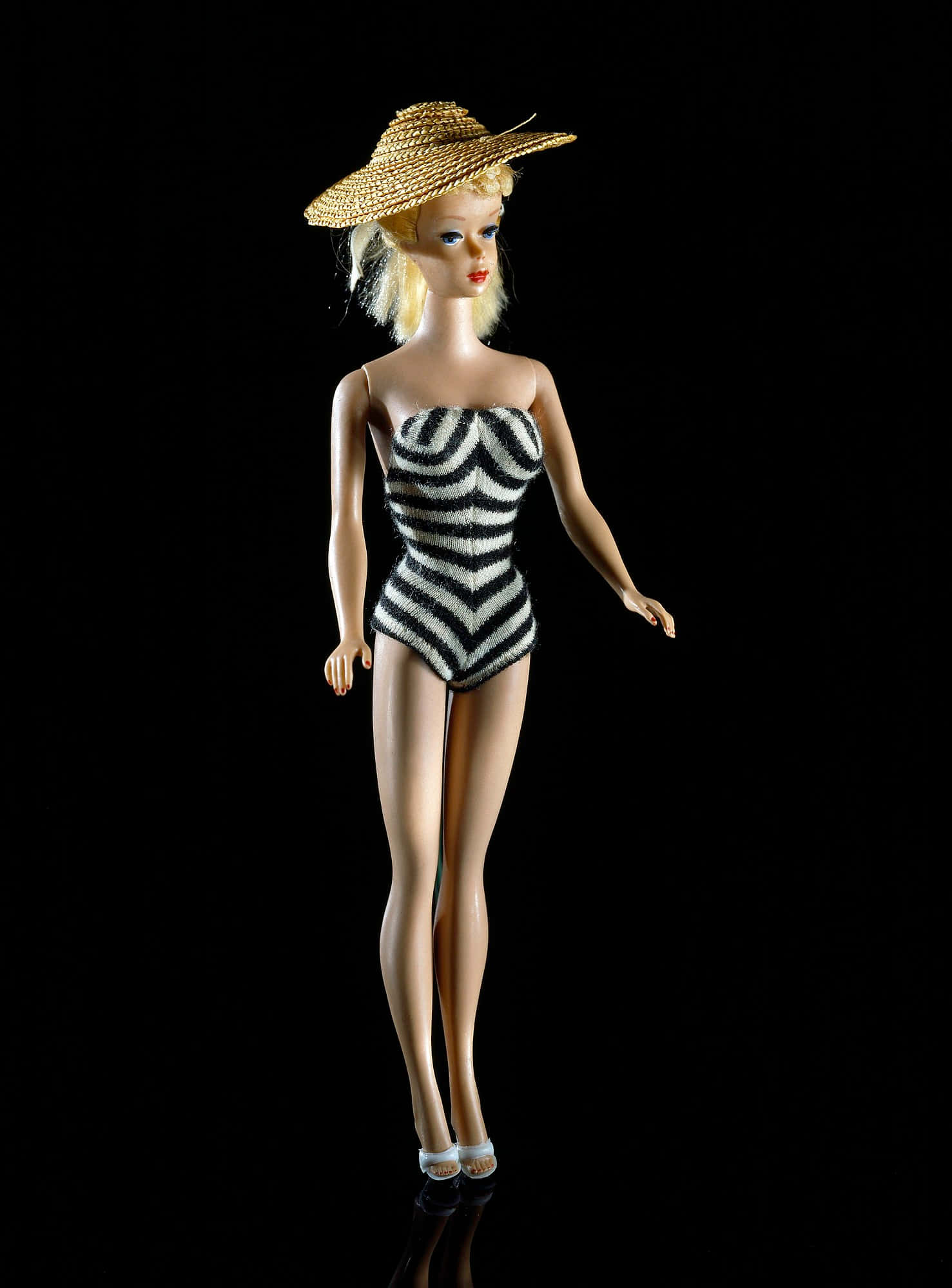 Barbie Doll 桌布 壁紙 — 一個復古芭比娃娃穿著黑白斑馬紋泳衣和草帽，在純黑背景前擺出姿勢。