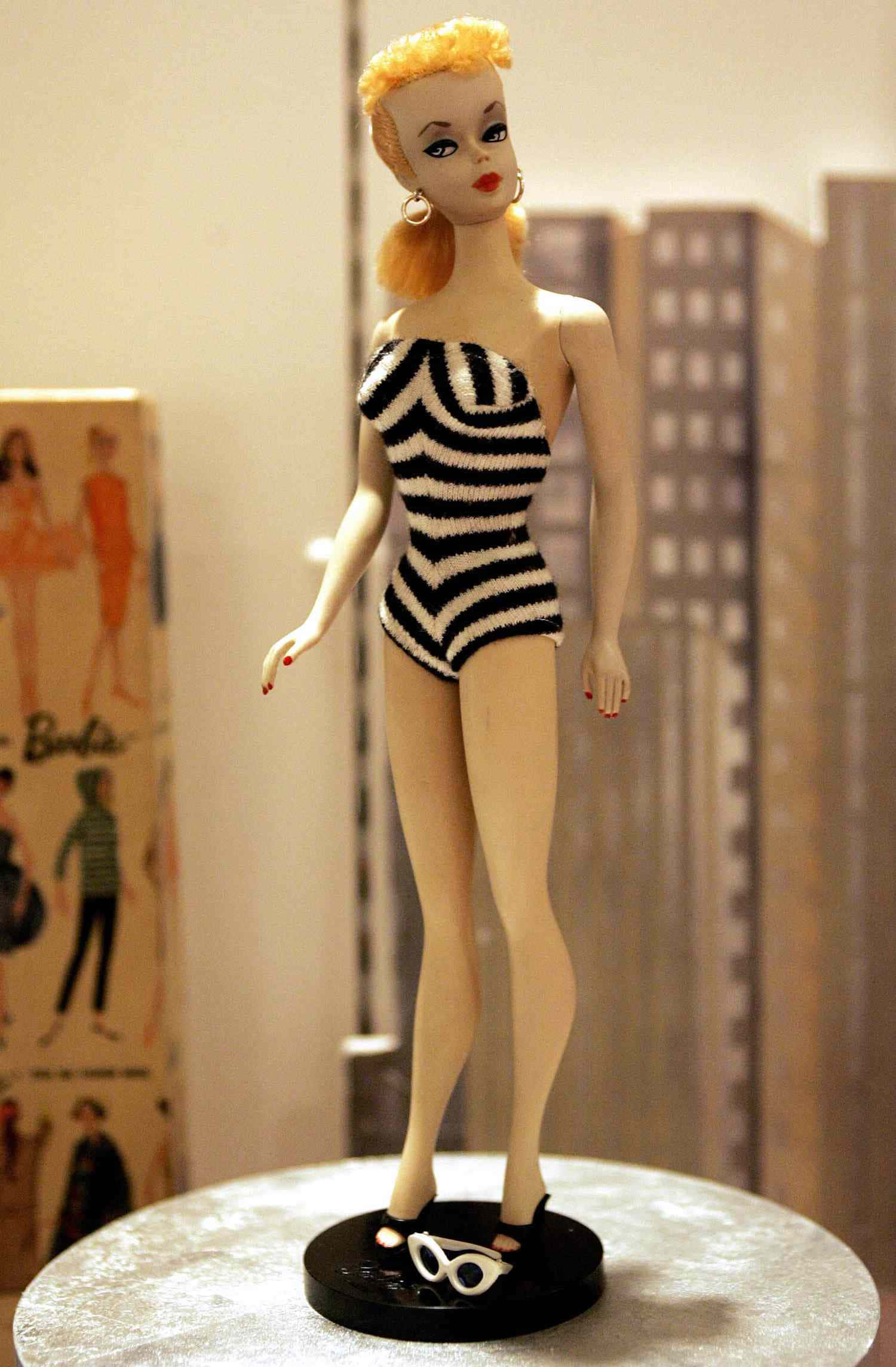 Barbie Doll 桌布 壁紙 — 一個復古芭比娃娃穿著黑白條紋泳衣，優雅地站在圓形底座上，旁邊放著泳鏡。