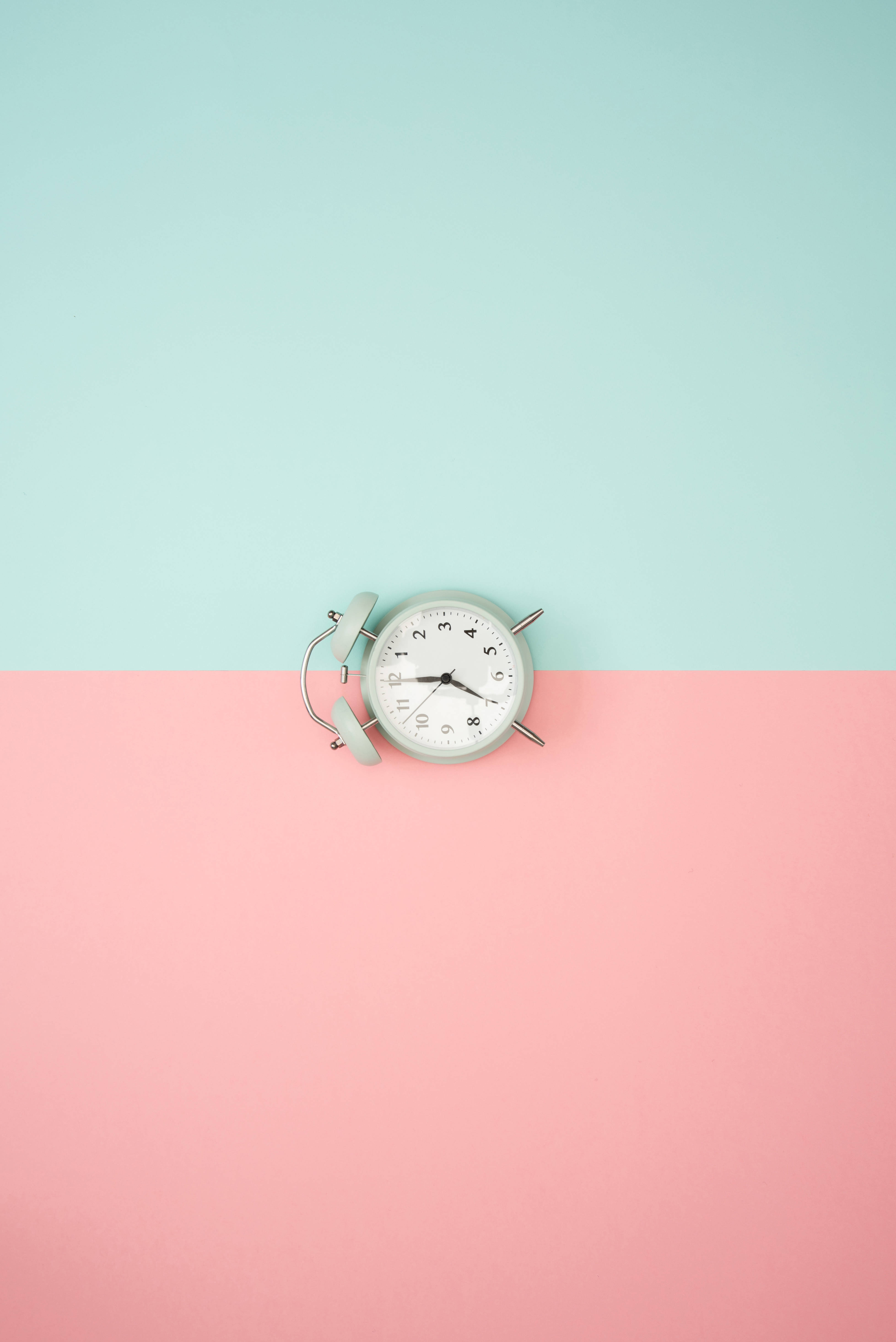 Clock 桌布 壁紙 — 一個復古薄荷綠色鬧鐘放在一個分為青綠色和粉紅色的柔和背景上。