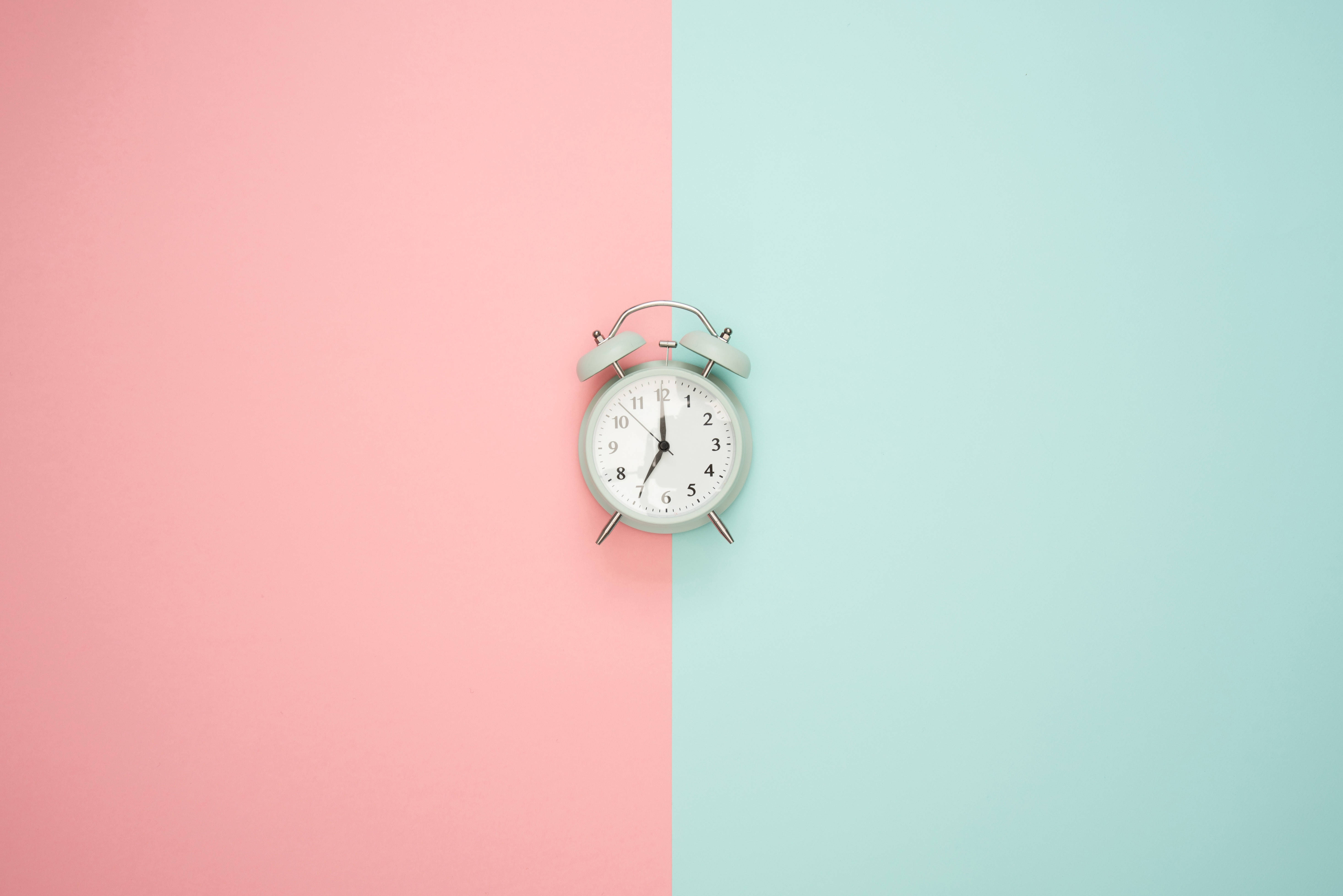 Clock 桌布 壁紙 — 一個復古薄荷綠色鬧鐘置於粉紅色和藍綠色的分割背景中央。