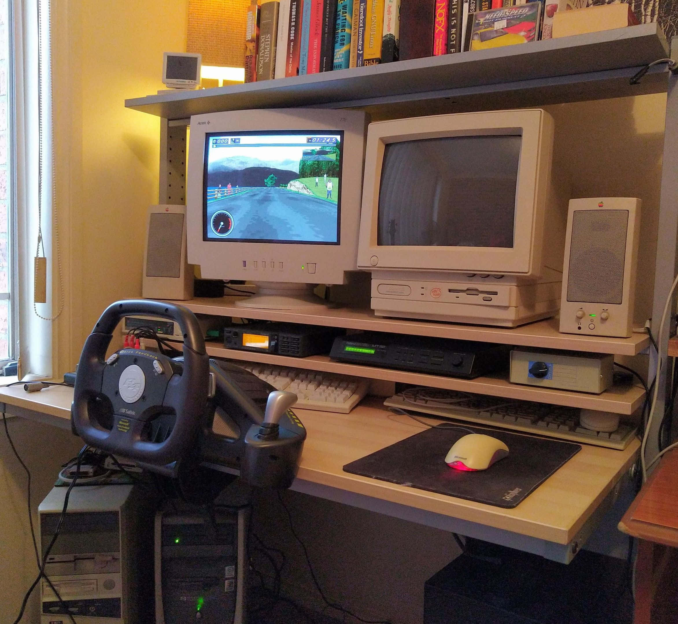 Old Pc 桌布 壁紙 — 一個復古遊戲設置，配備方向盤和兩台CRT顯示器，在溫暖照明的房間中顯示賽車遊戲。