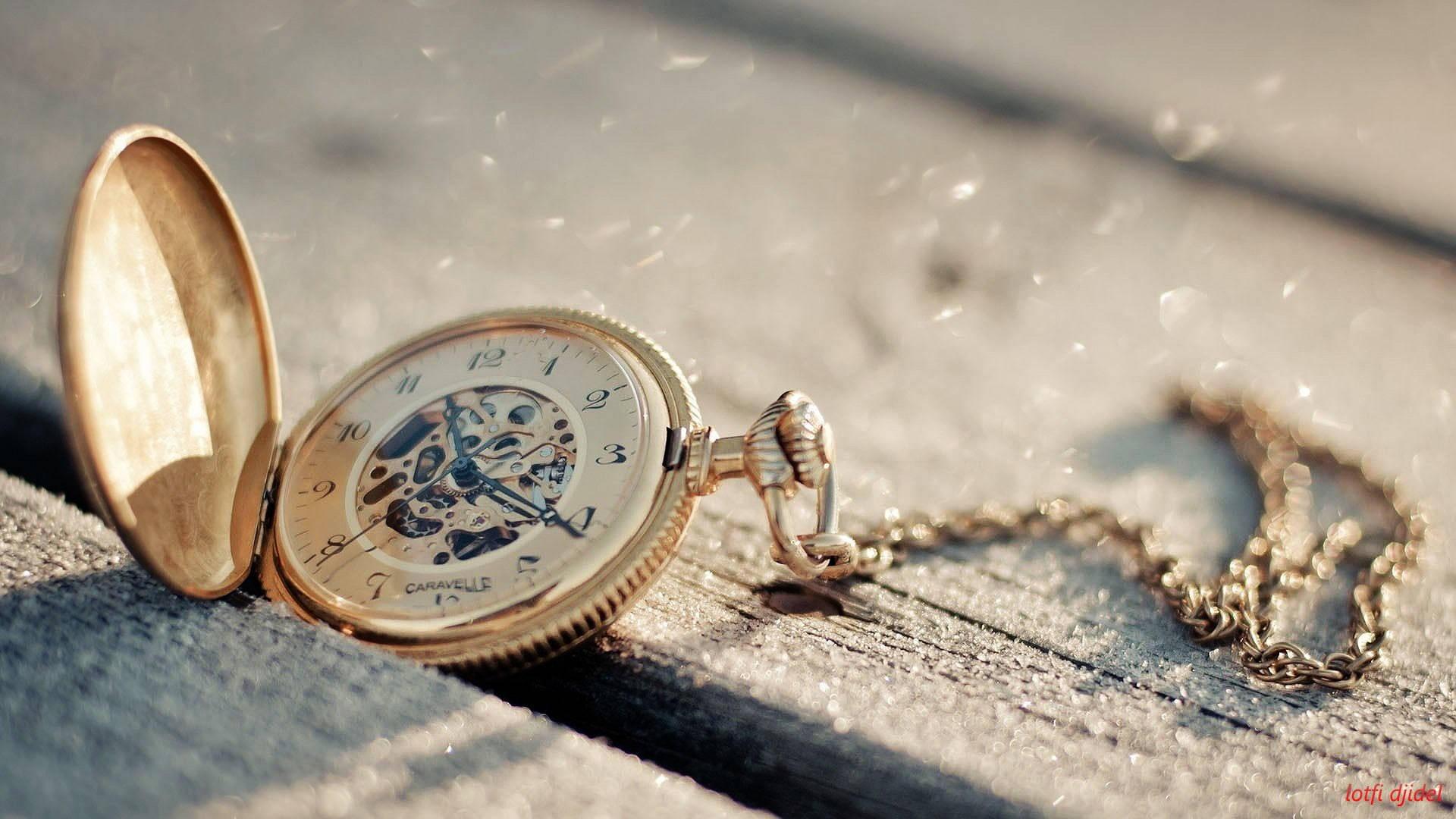 Clock 桌布 壁紙 — 一個復古金色懷錶，露出齒輪，打開放在經風化的木頭上，溫暖陽光下飄浮著灰塵顆粒。