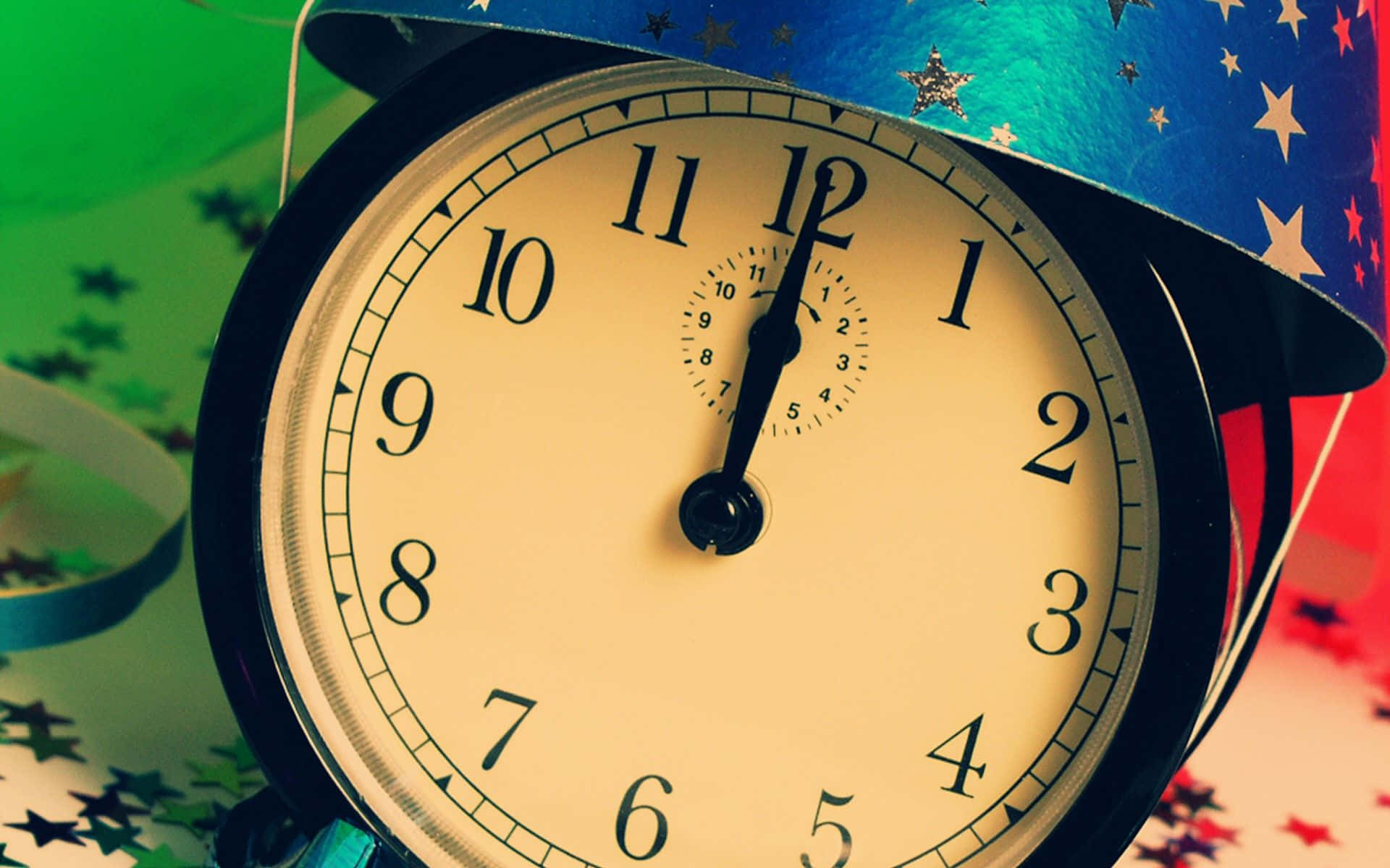 Clocks 桌布 壁紙 — 一個復古鬧鐘戴著星星圖案的藍色帽子，在午夜時分置身於綠色、紅色和星星形狀的節日五彩紙屑中。