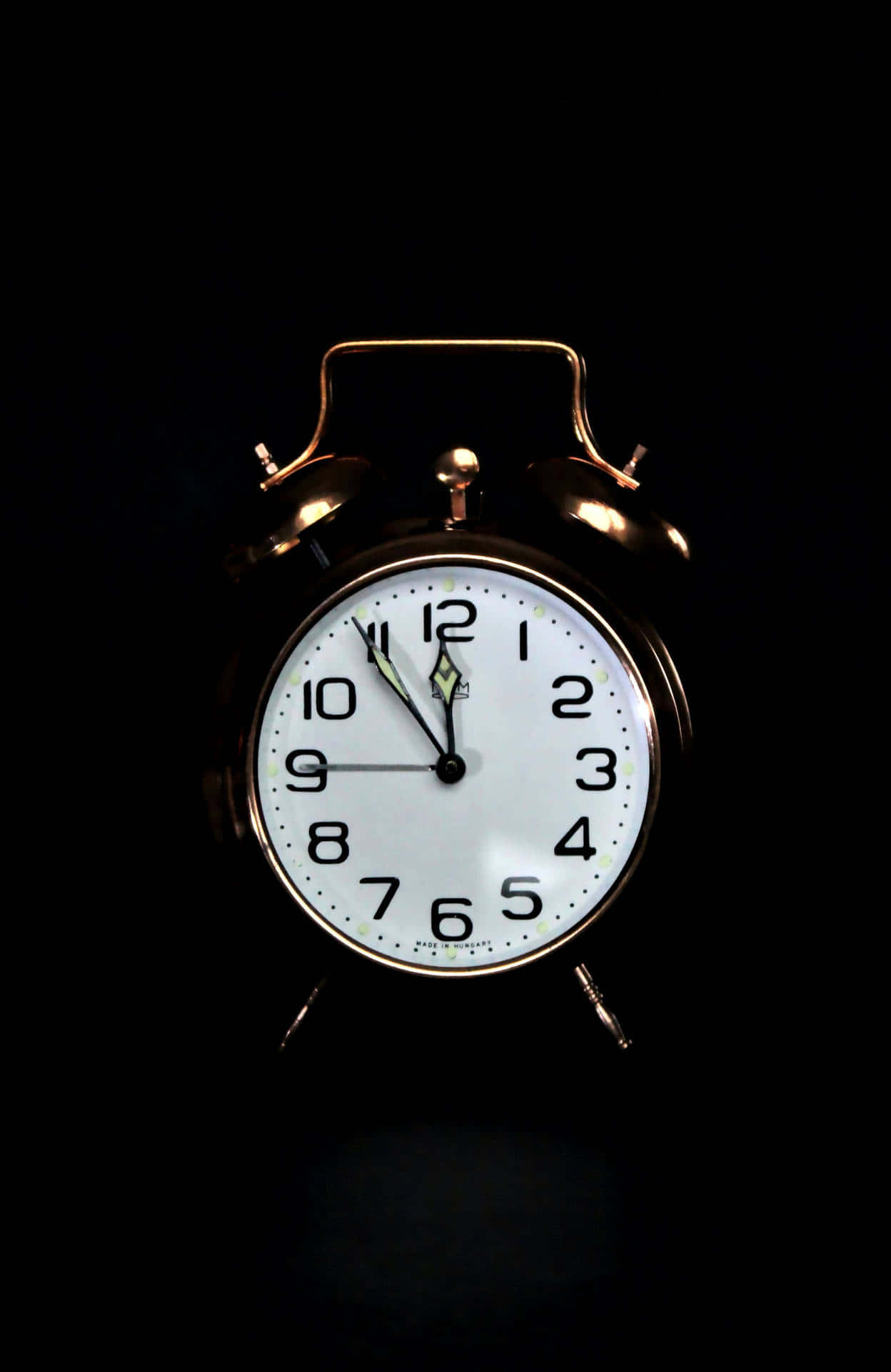 Clocks 桌布 壁紙 — 一個復古黃銅鬧鐘，白色錶盤搭配黑色數字，在漆黑背景中發光。